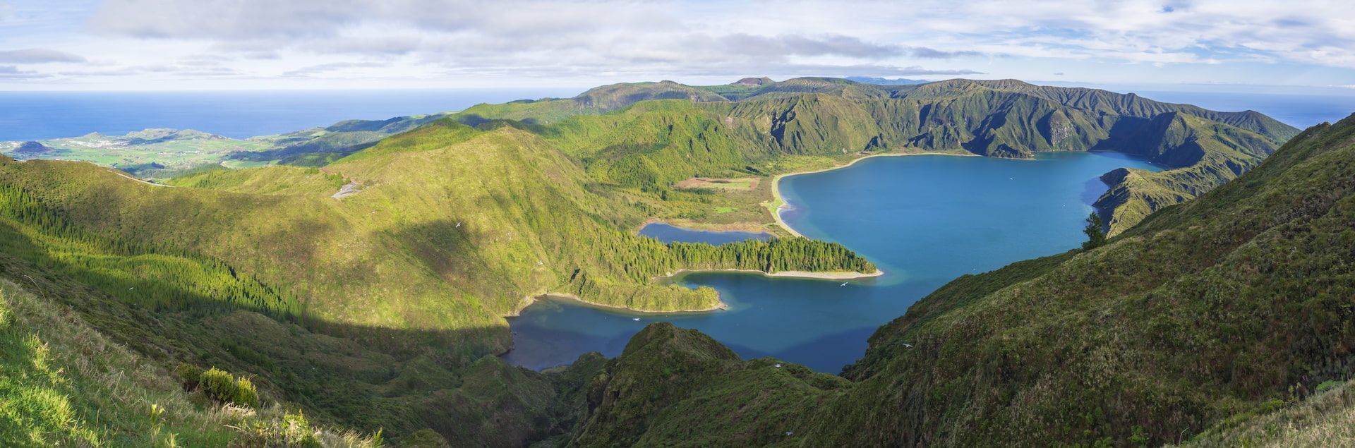 Tu cherches un voyage pour te plonger dans la nature et la plage ou faire du trekking ? Alors pars avec WeRoad aux Açores pour vivre toutes ces expériences ! Photo panoramique du lac de Fogo à São Miguel - WeRoad