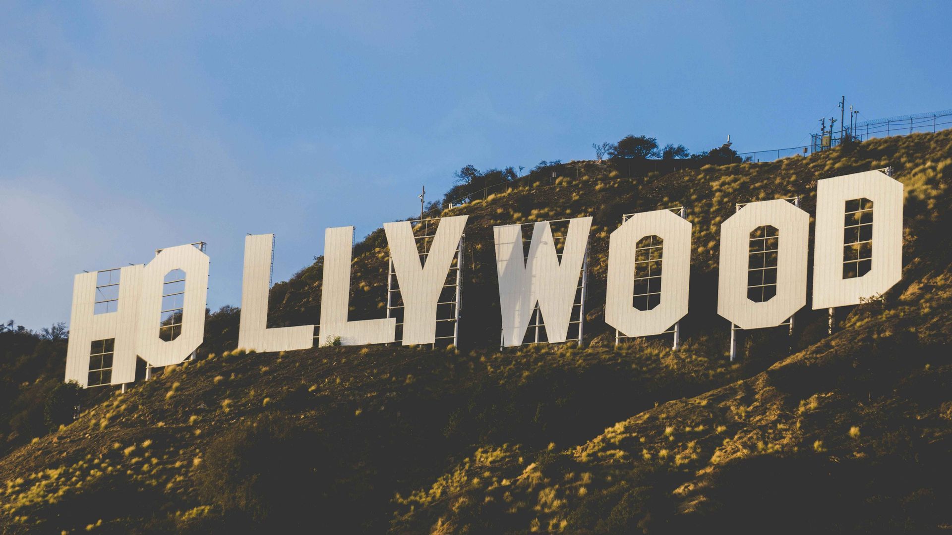 La grande insegna bianca di Hollywood si trova su una collina erbosa sotto un cielo azzurro e limpido.