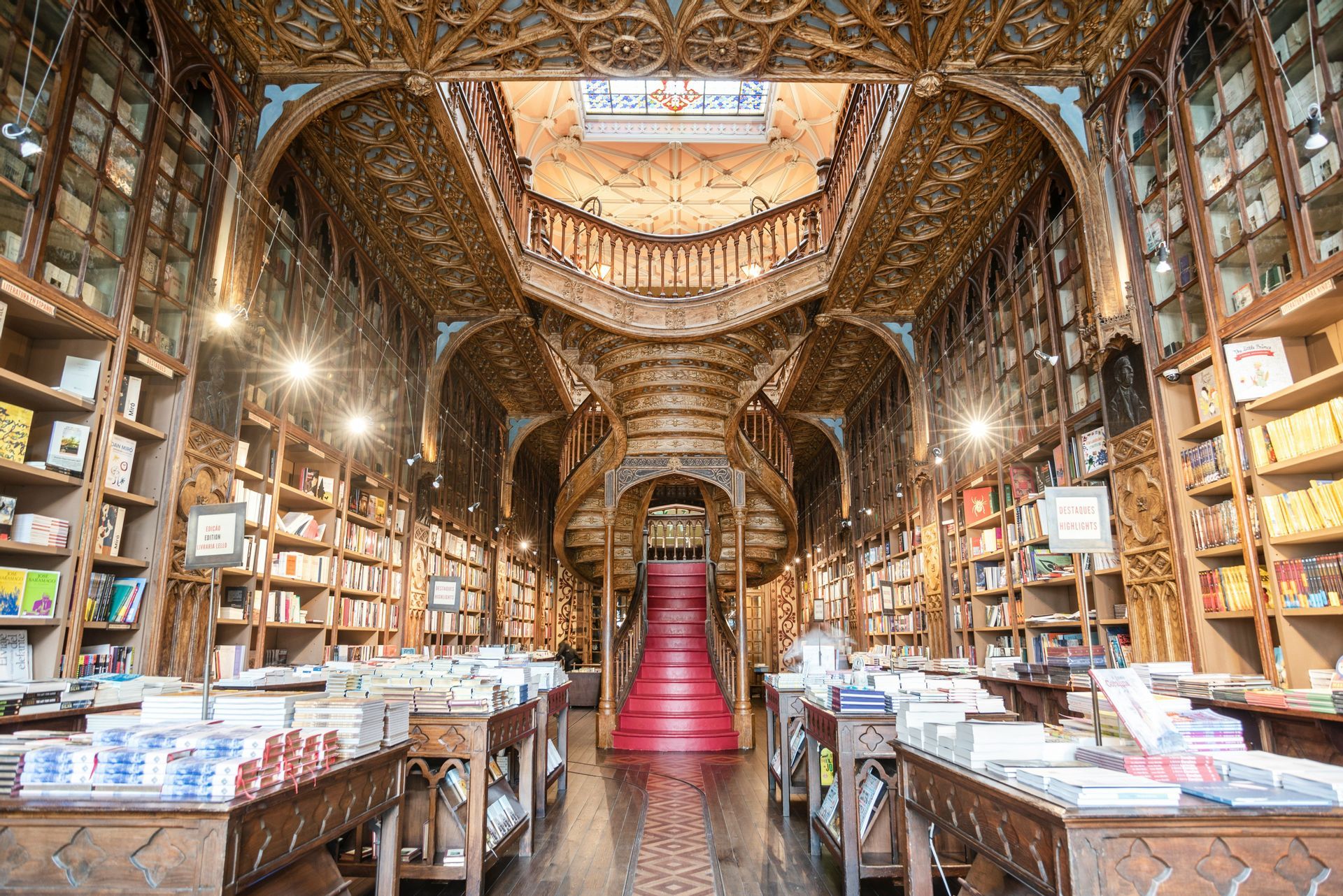 L'interno maestoso di una biblioteca sontuosa, con una scala curva in legno dai gradini rossi, circondata da altissimi scaffali.