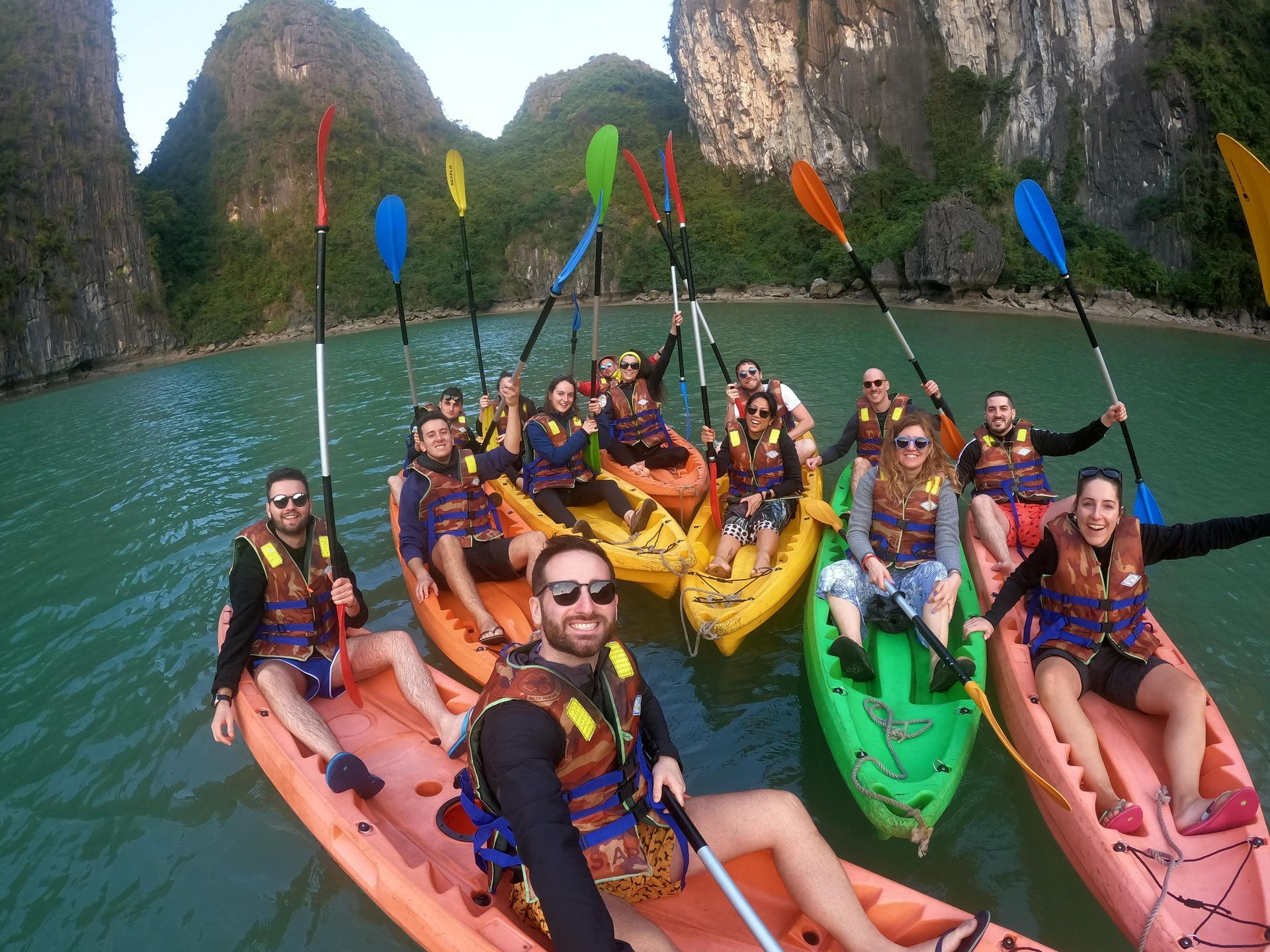 Eine WeRoad-Gruppe macht ein Selfie beim Kajakfahren auf dem Wasser zwischen großen Felsformationen.
