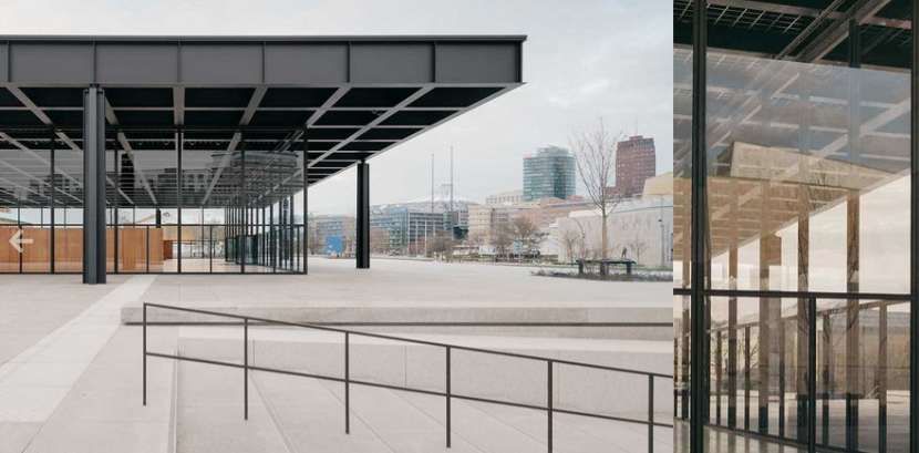 Un edificio moderno con una struttura in acciaio nero e pareti in vetro si erge su un'ampia piazza in cemento contro lo skyline della città.