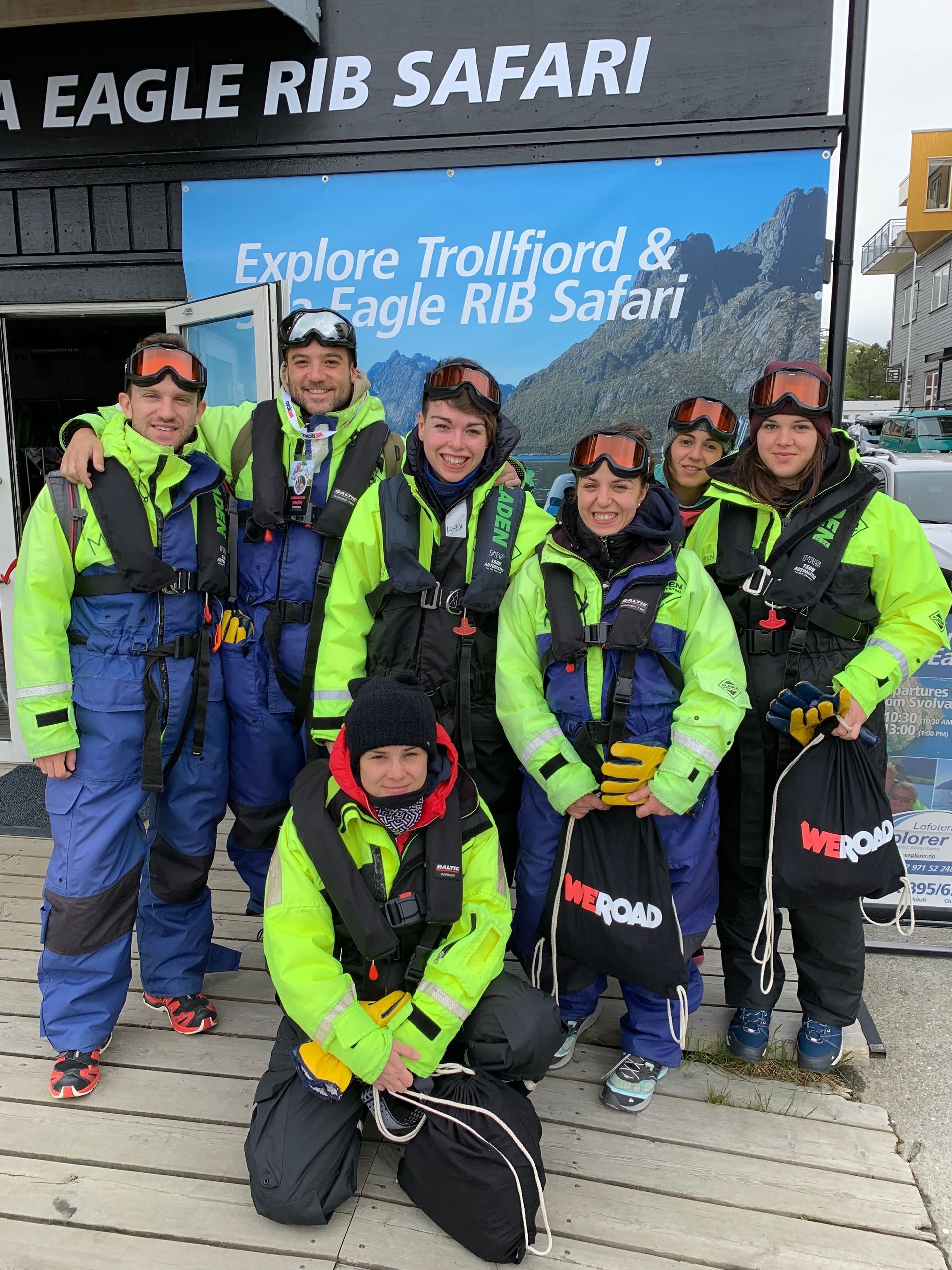 A WeRoad group trip poses for a photo in waterproof gear and life vests before a boat safari.