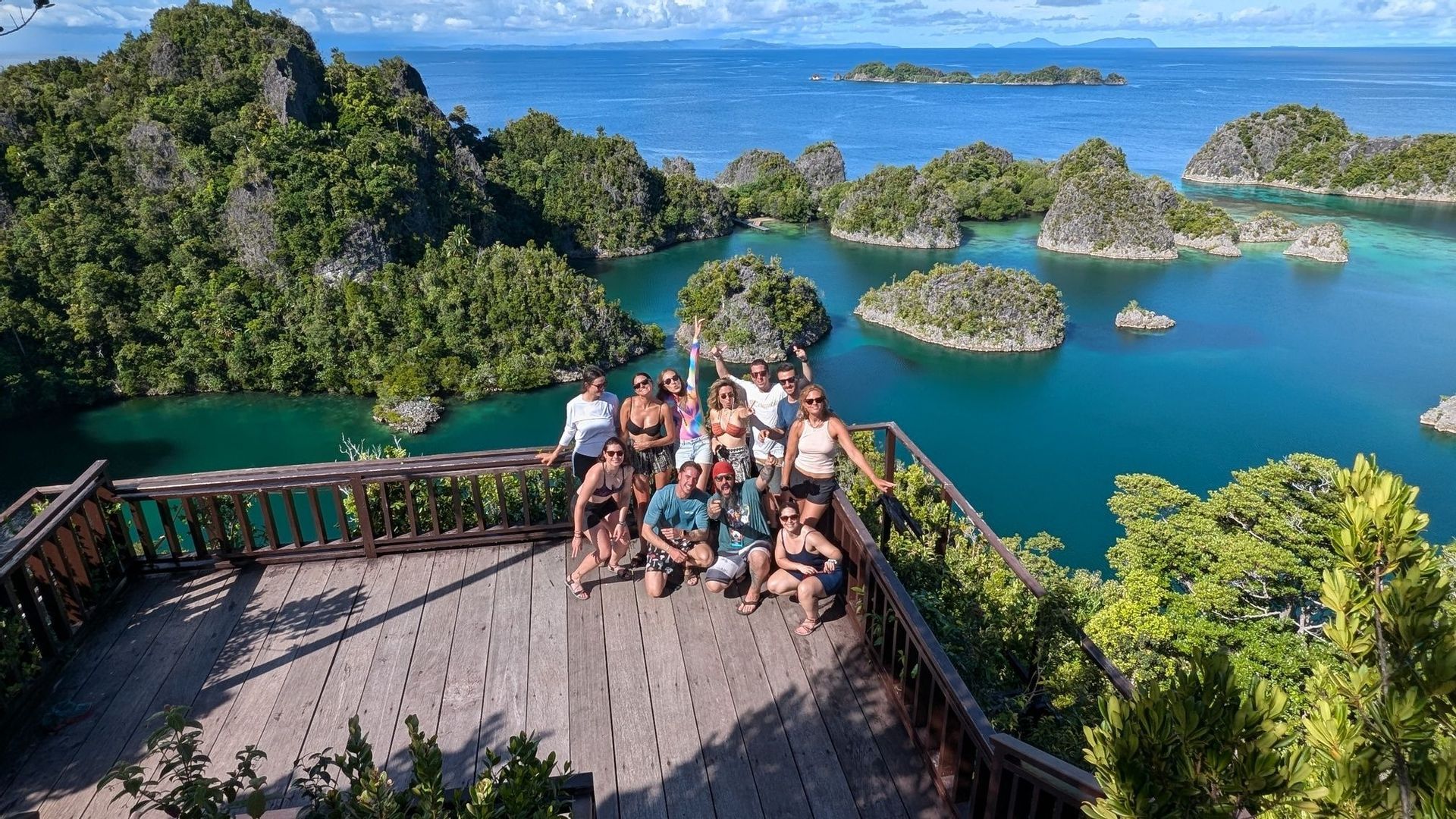 Un grupo de WeRoad posa para una foto en un mirador de madera, con vistas a una bahía tropical repleta de numerosas islas verdes y rocosas.