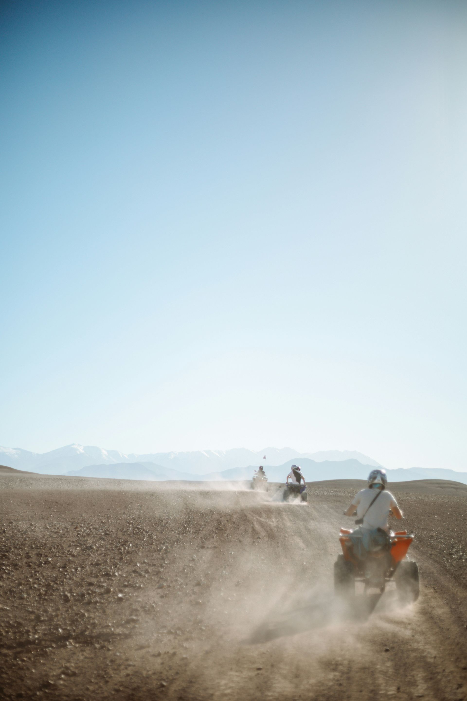 Un viaggio di gruppo WeRoad in quad su un sentiero polveroso nel deserto, con le montagne visibili in lontananza.