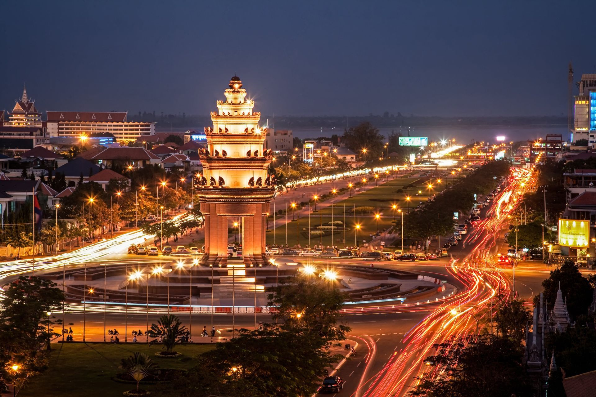 Un monumento iluminado en una rotonda de la ciudad por la noche, capturado con una exposición larga para mostrar estelas de luces de tráfico.