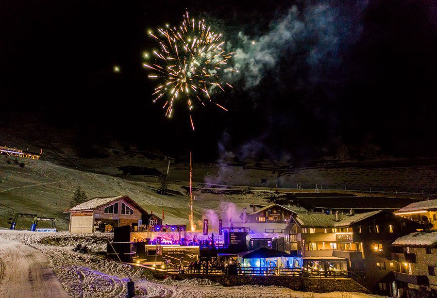 I fuochi d'artificio illuminano il cielo notturno sopra una località di montagna innevata dove un gruppo WeRoad festeggia.
