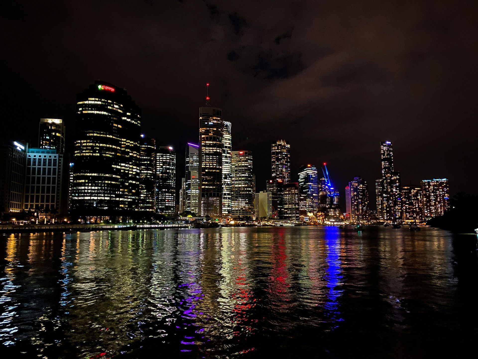 Un horizon urbain moderne illuminé la nuit, avec les lumières des bâtiments se reflétant sur la surface de l'eau.