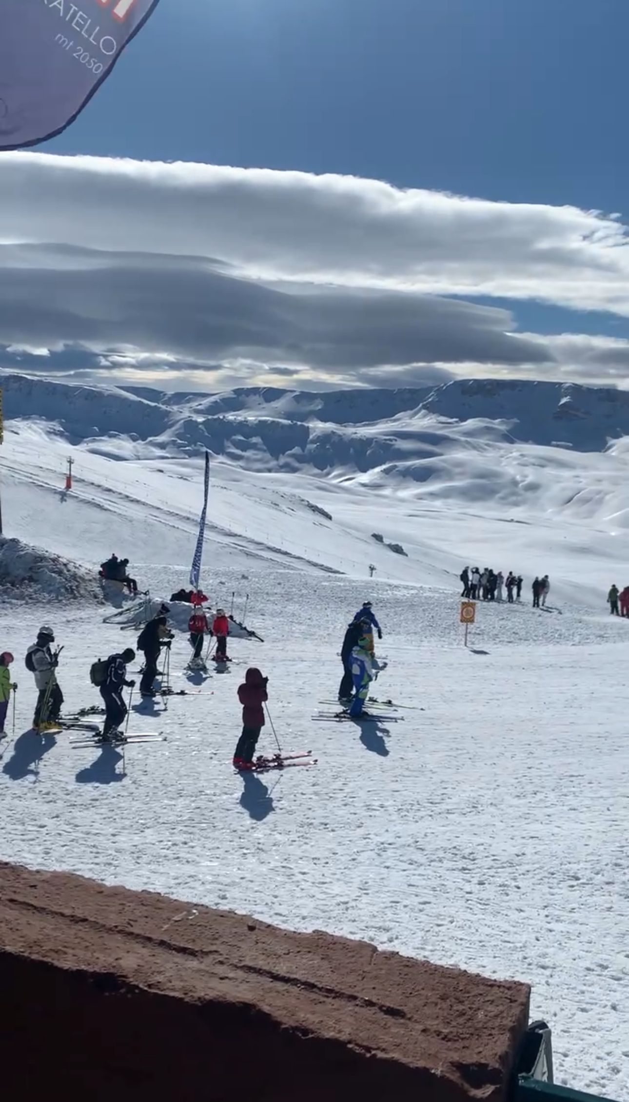 Un viaggio di gruppo WeRoad su una pista da sci innevata, con vista panoramica su montagne coperte di neve sotto un cielo parzialmente nuvoloso.