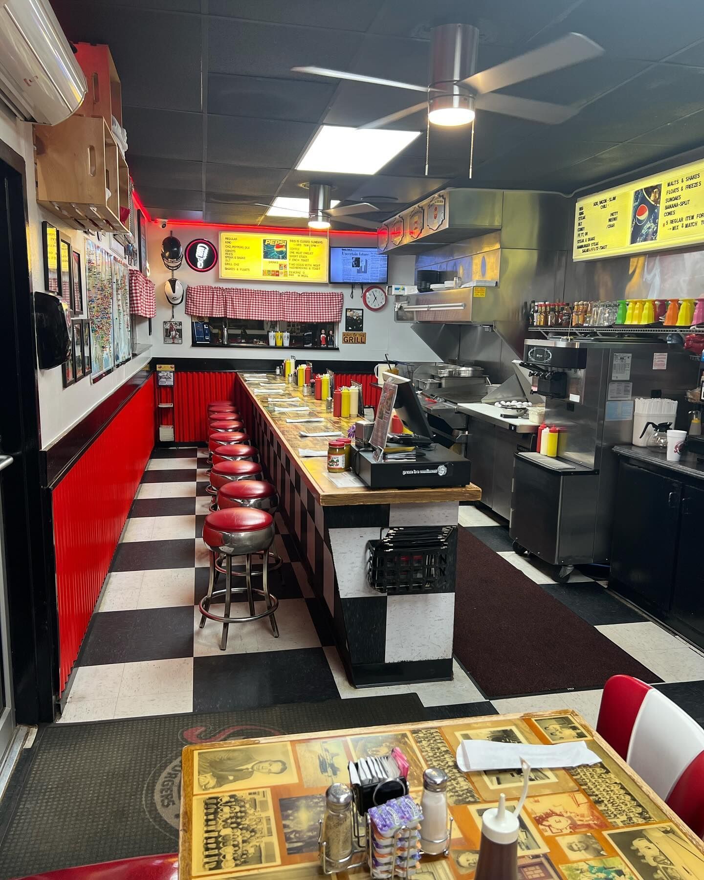 El interior de un diner americano de estilo retro con una barra larga, taburetes rojos y un suelo de cuadros blancos y negros.