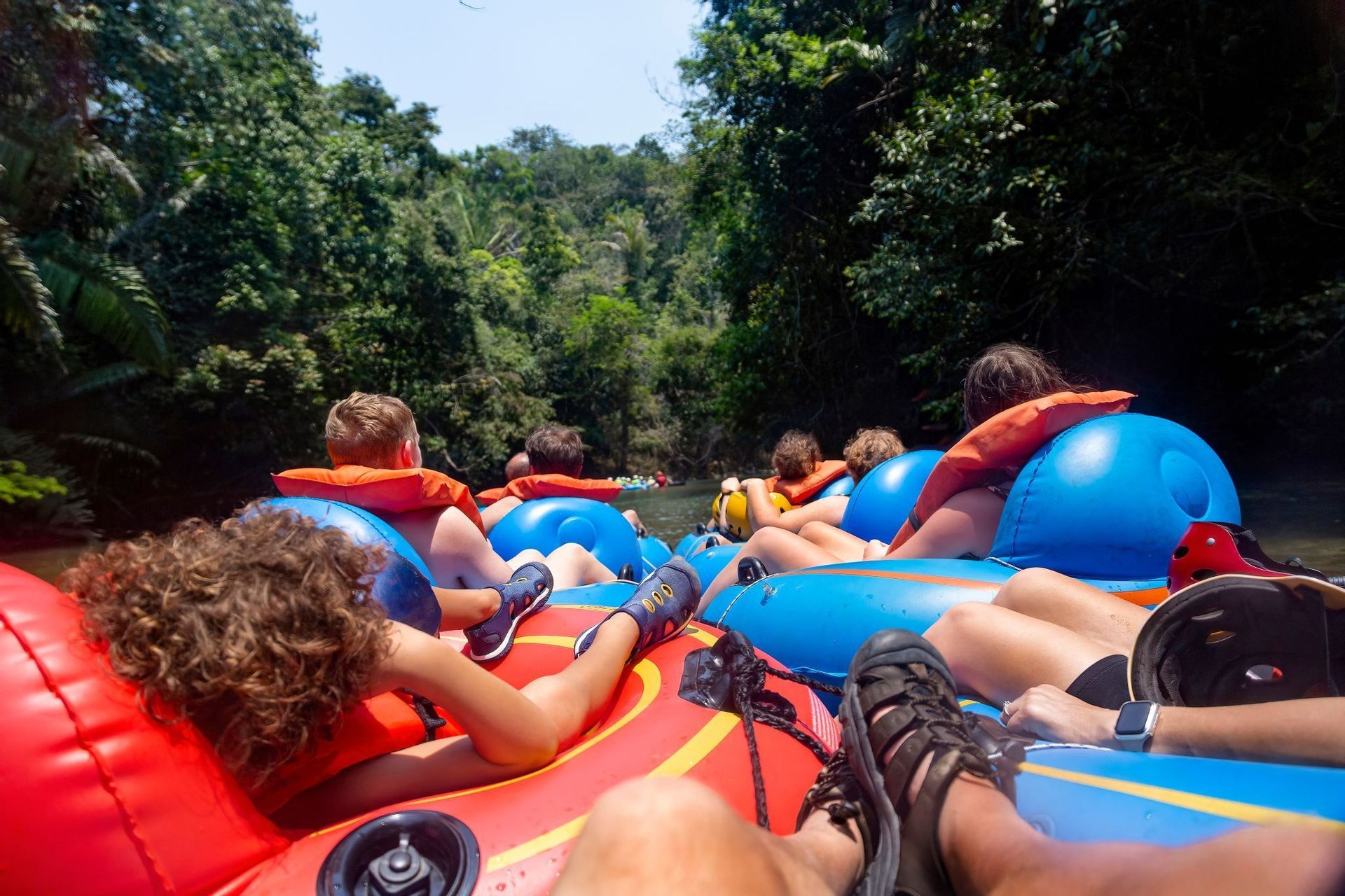 Un voyage de groupe WeRoad en gilet de sauvetage, descendant une rivière en bouée à travers une jungle luxuriante et verte.