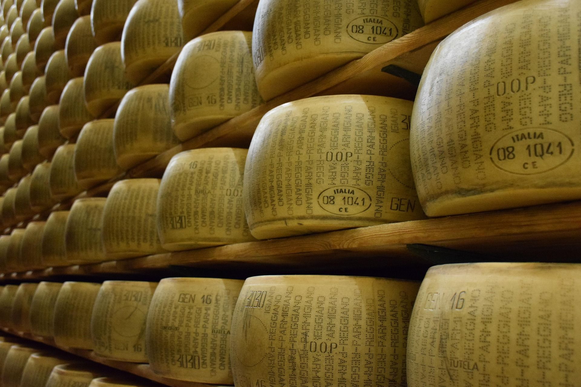 Forme di Parmigiano-Reggiano sono impilate su scaffali di legno per stagionare in un magazzino.