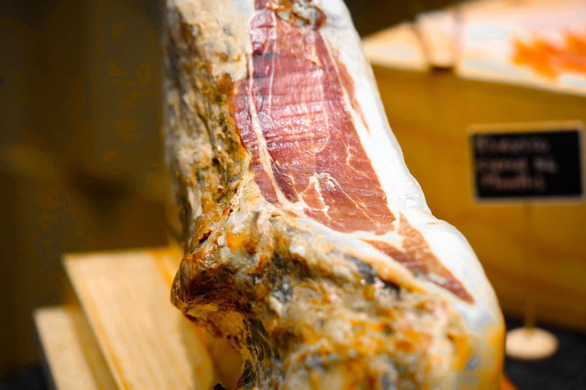 Un primo piano di un'intera coscia di prosciutto stagionato in esposizione, che rivela la carne rossa marmorizzata e il grasso bianco.