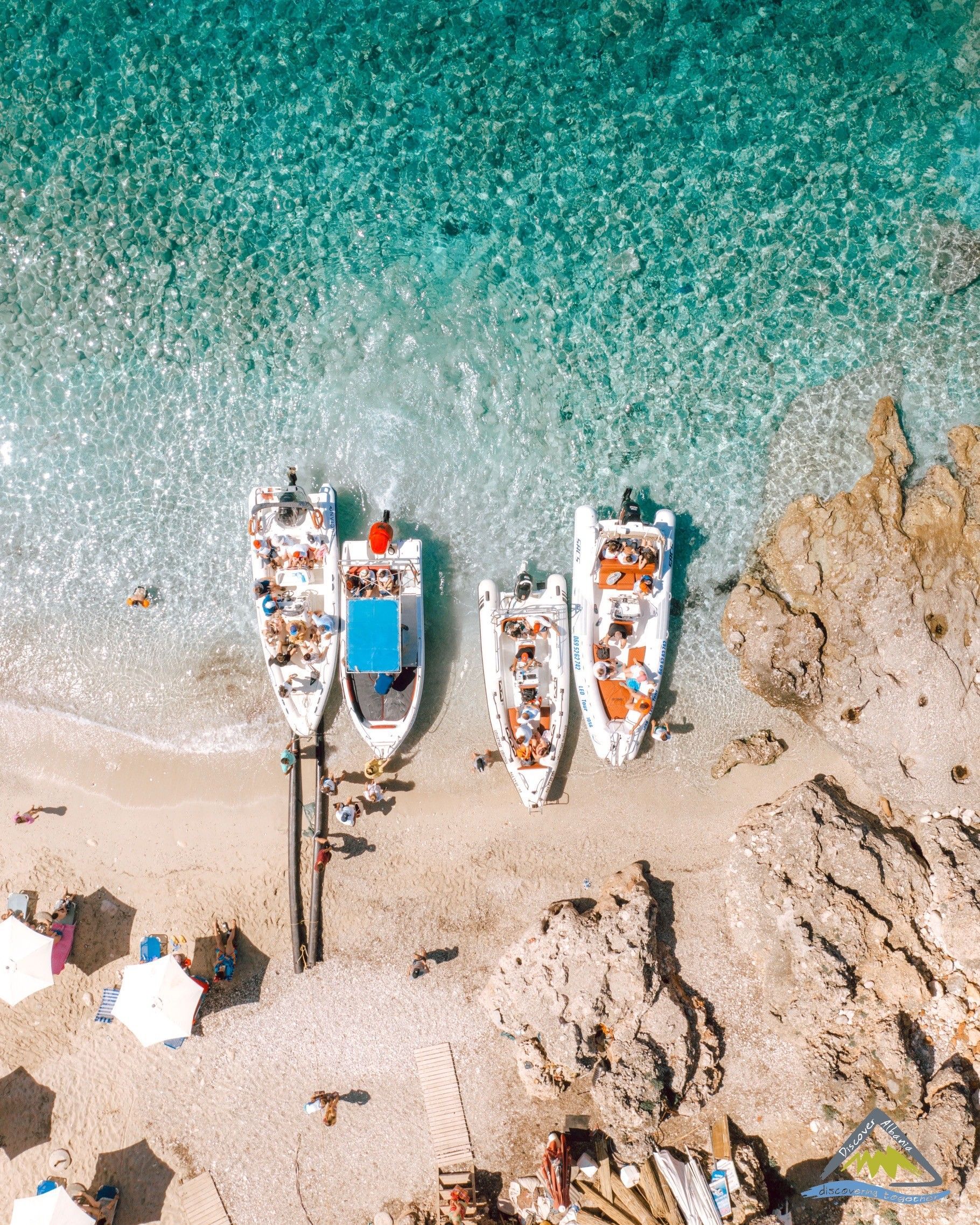Una vista aérea de un viaje en grupo de WeRoad con varios barcos varados en una playa de arena con agua turquesa cristalina.