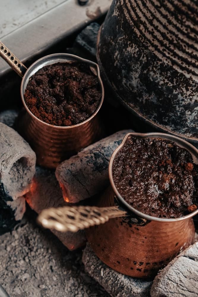 Due tradizionali bricchi di rame con caffè in lenta infusione su braci ardenti.