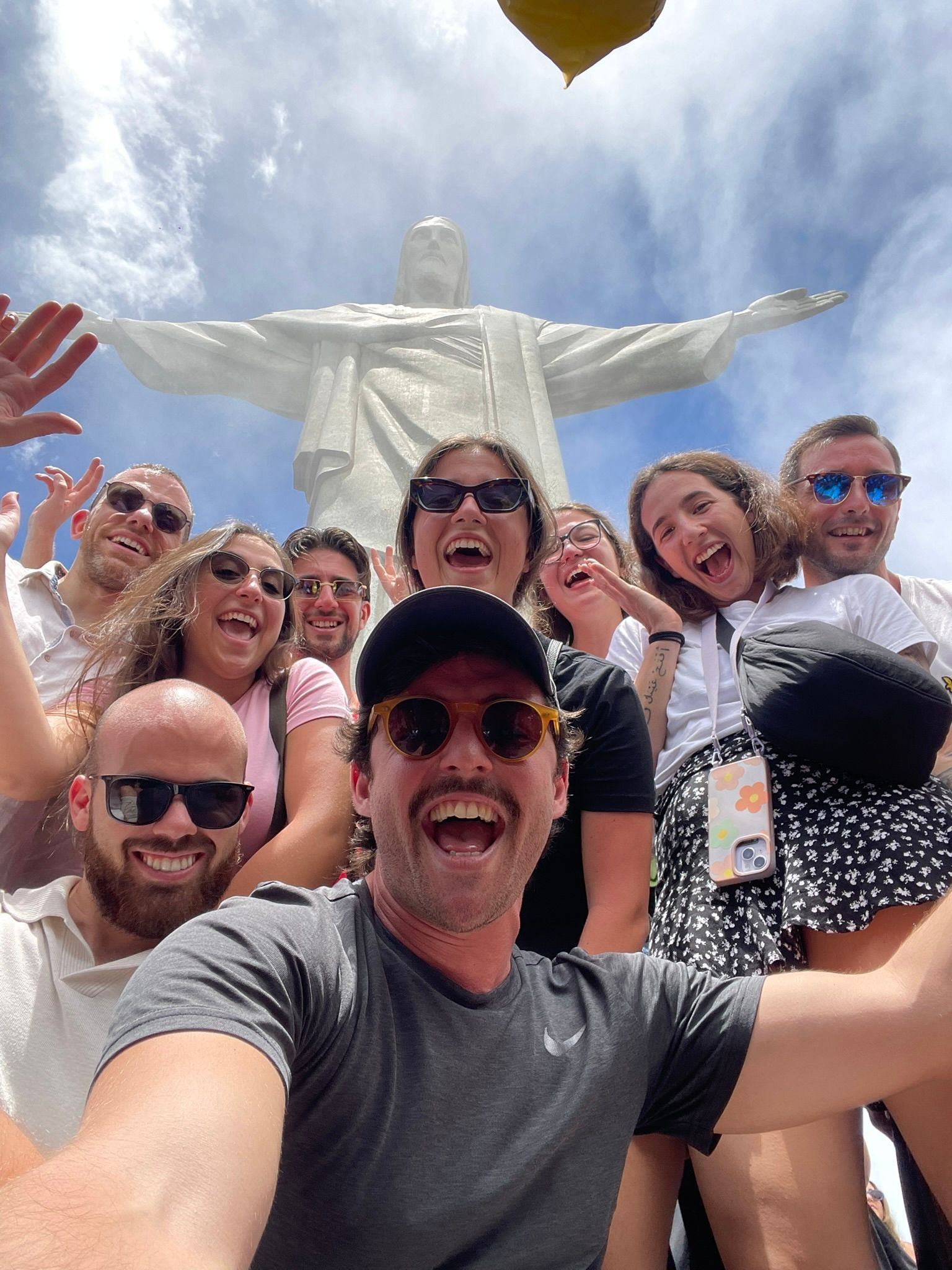 Un viaggio di gruppo WeRoad scatta un selfie sorridente con la statua del Cristo Redentore sullo sfondo.