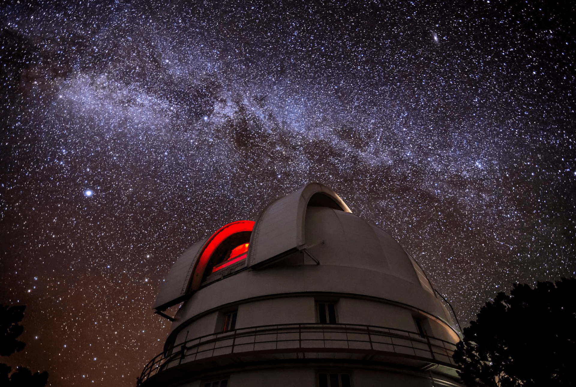 Un osservatorio astronomico con la sua cupola aperta contro un cielo notturno pieno delle stelle della Via Lattea