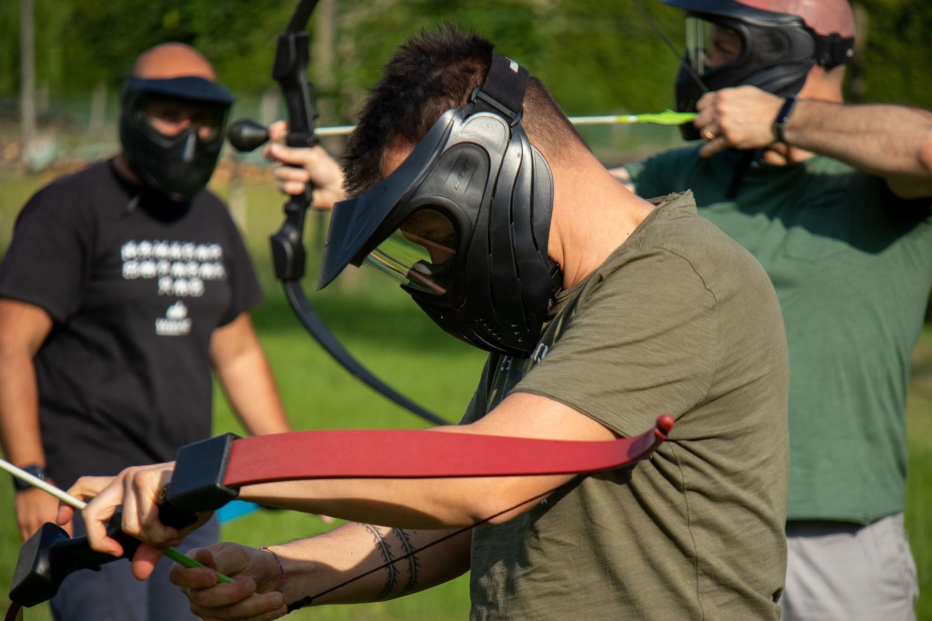 Un uomo di un viaggio di gruppo WeRoad indossa una maschera protettiva mentre si prepara a tirare con l'arco e la freccia durante una sessione di tiro con l'arco.