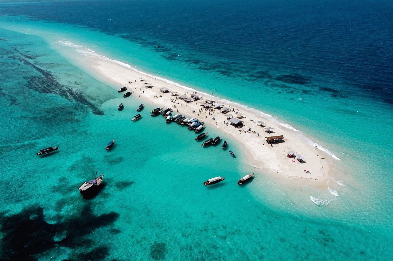 Vista aerea di un banco di sabbia bianca immerso in un mare turchese, con un gruppo WeRoad e numerose imbarcazioni radunate.