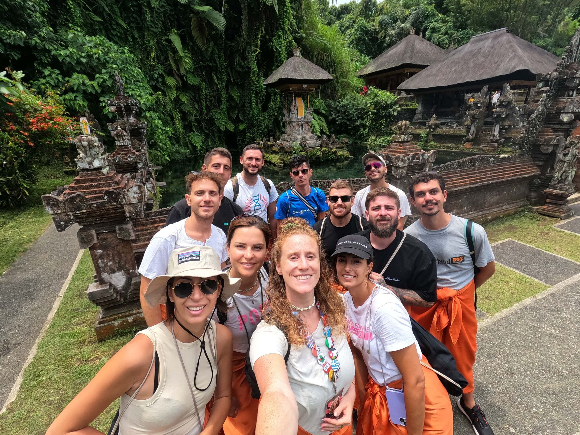 Un viaje en grupo de WeRoad se toma una selfie frente a un templo de piedra ornamentado rodeado de exuberante vegetación.