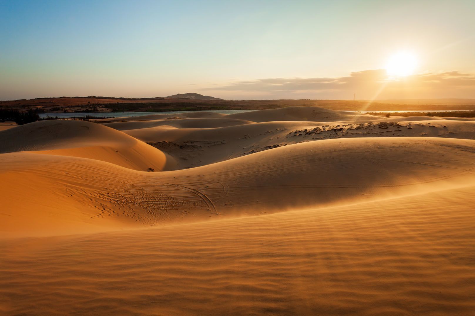 Dune di sabbia soffici sotto un tramonto luminoso con increspature che si formano sulla superficie del deserto.