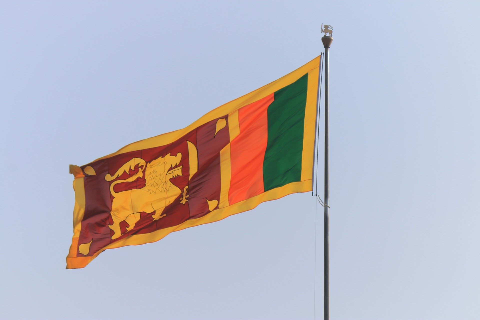 La bandiera nazionale dello Sri Lanka, con un leone d'oro, che sventola su un'asta contro un cielo azzurro chiaro.