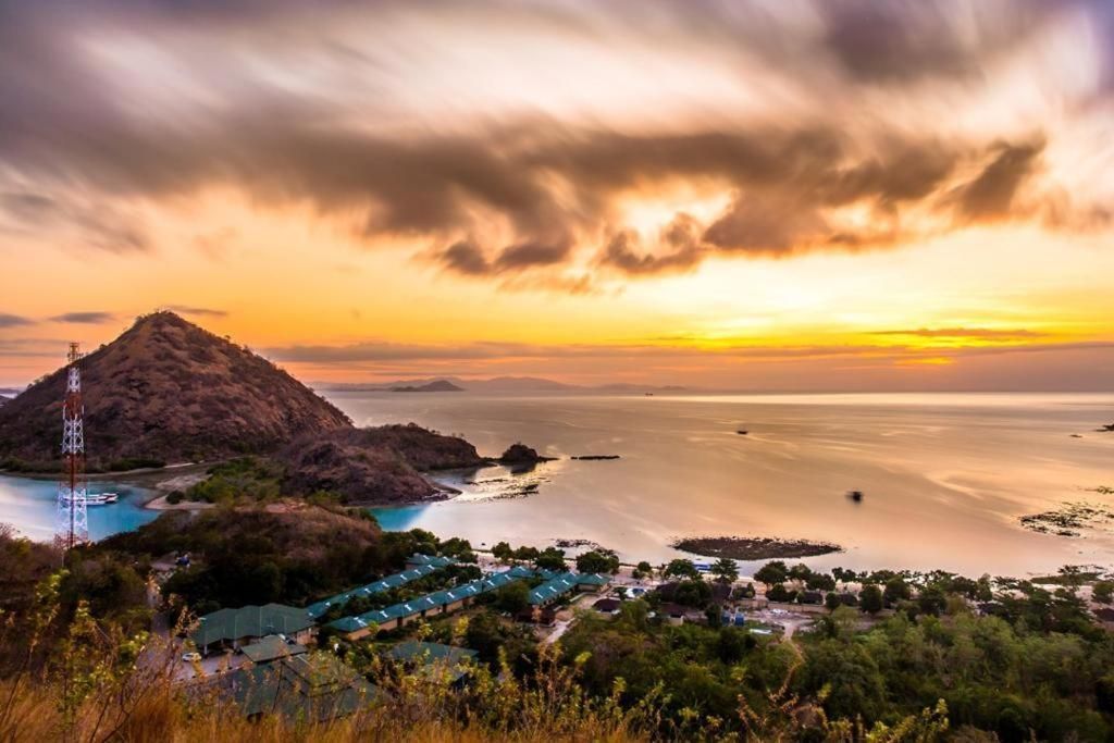 Vue en plongée à longue exposition d'une ville côtière et d'une grande colline près d'une baie au coucher de soleil doré.