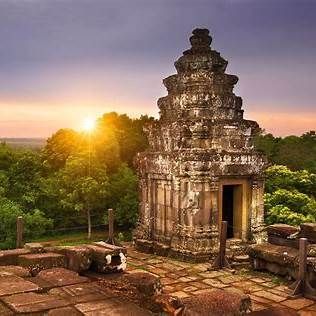 Un antico tempio in pietra a più livelli domina una fitta foresta mentre il sole tramonta all'orizzonte, proiettando un bagliore dorato.