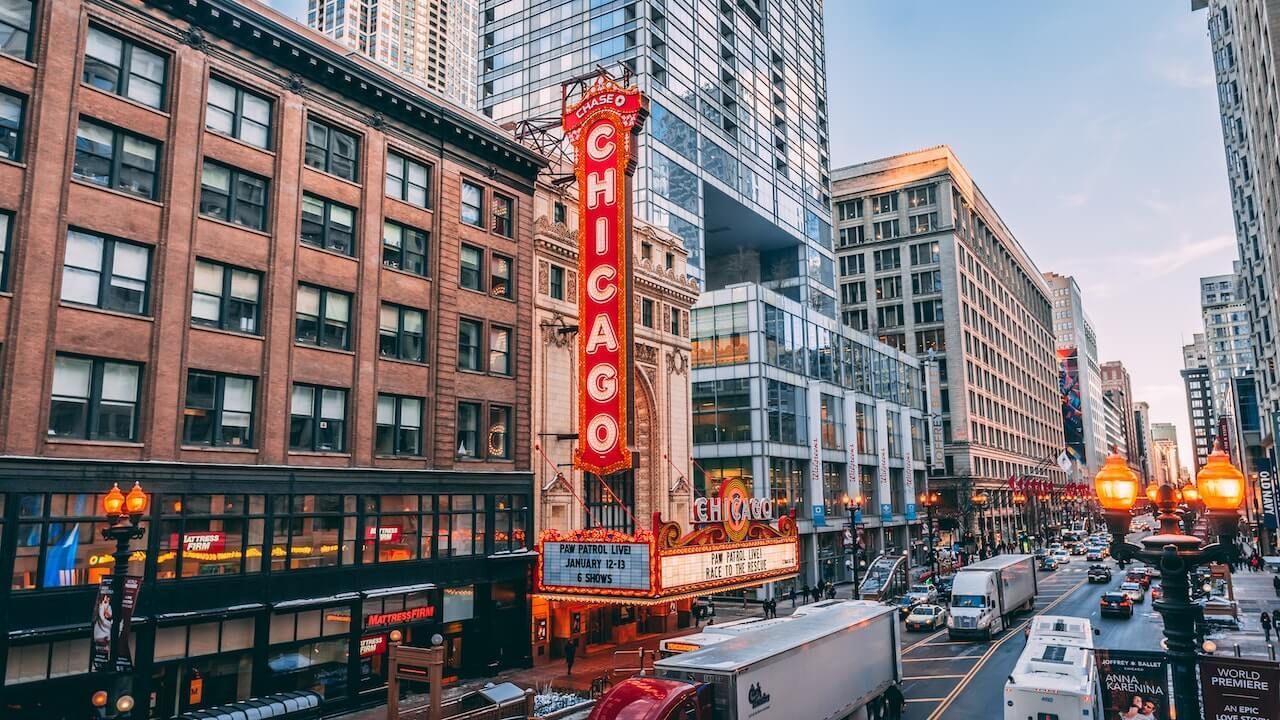 L'iconica insegna verticale del Chicago Theatre illuminata su una trafficata strada cittadina con traffico e moderni grattacieli