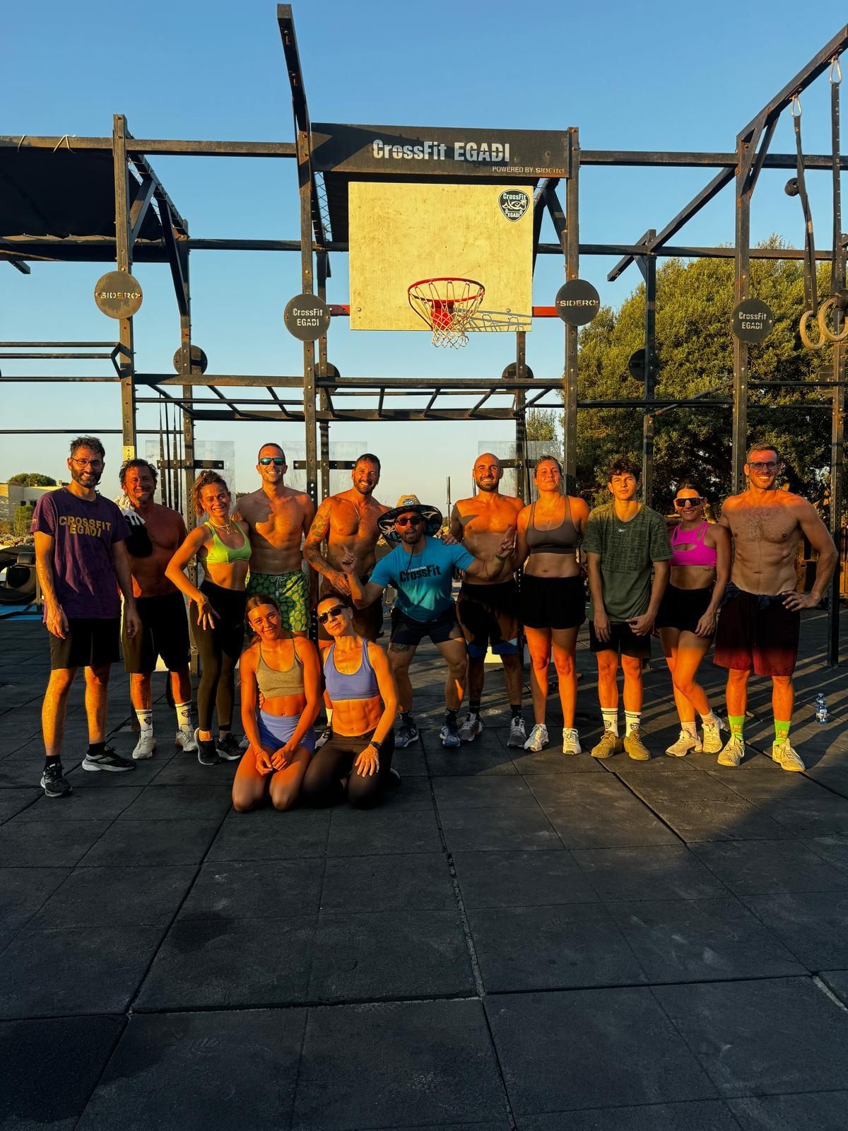 Un gruppo WeRoad in posa per una foto in una palestra CrossFit all'aperto con un canestro da basket sullo sfondo.