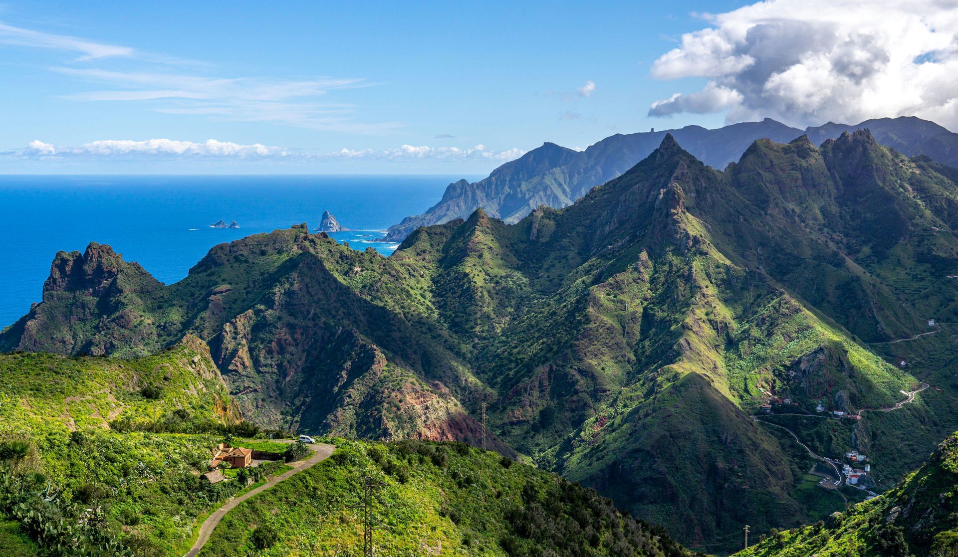 Vista panoramica su una catena montuosa aspra e verde che digrada nell'oceano blu in una giornata di sole.