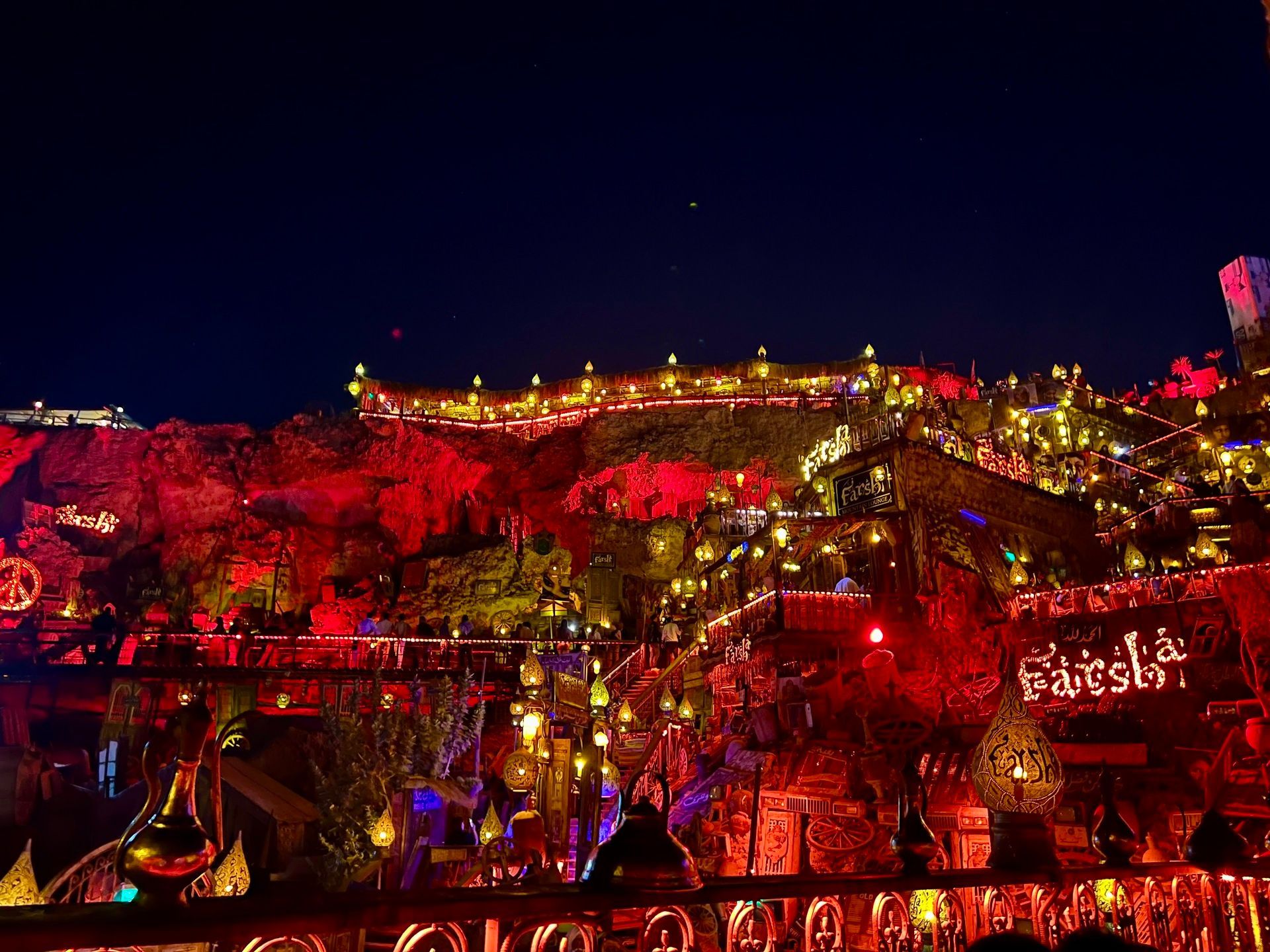 Una location all'aperto su più livelli, ricavata in una parete rocciosa, illuminata di notte da centinaia di lampade e lanterne dai toni caldi.
