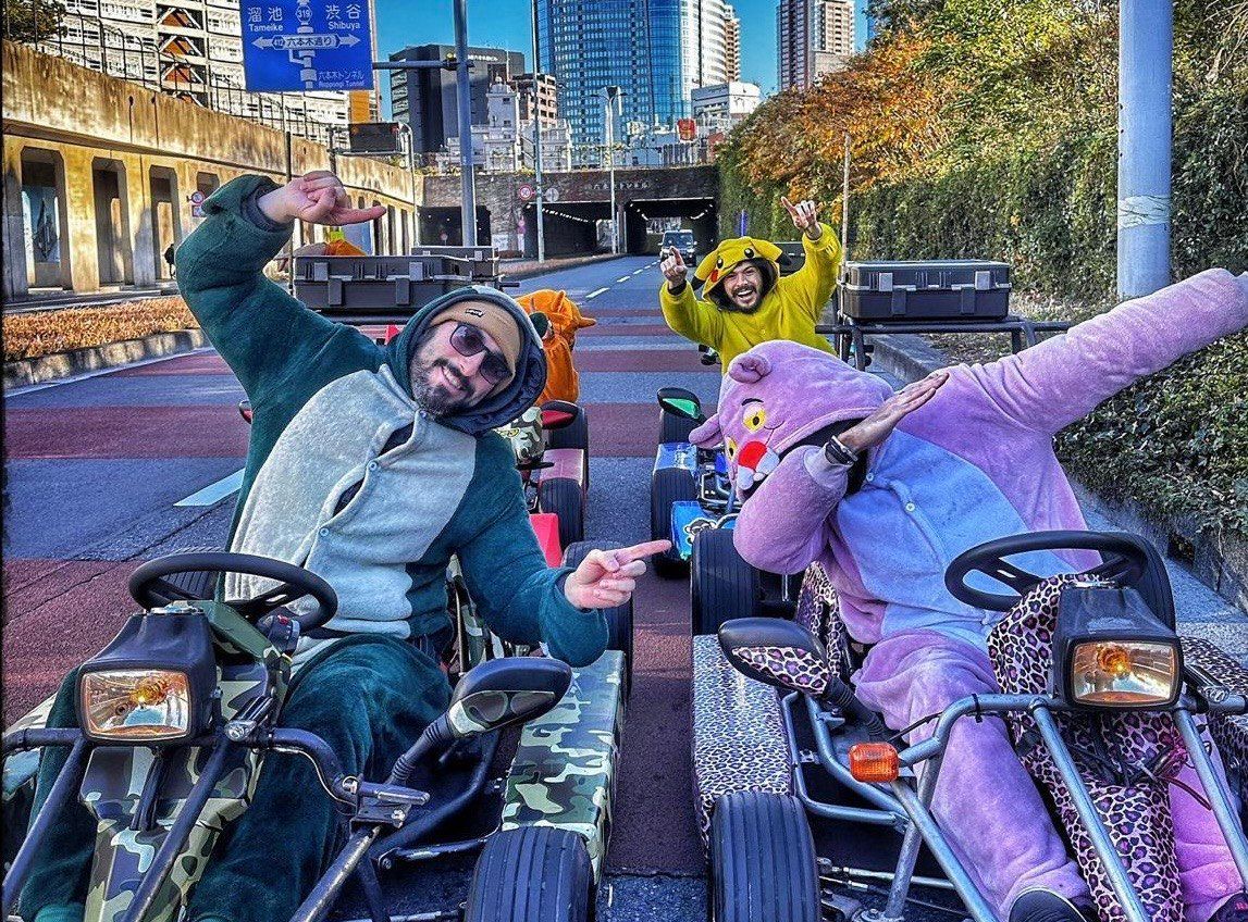 Un viaggio di gruppo WeRoad con uomini in costumi da personaggio che posano su go-kart in una strada cittadina a più corsie.