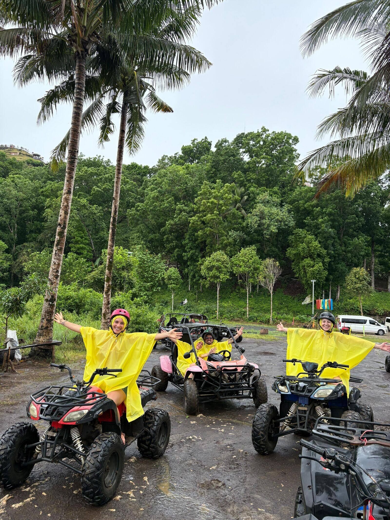 Un gruppo WeRoad in viaggio con poncho antipioggia gialli, in posa su quad e un buggy nella giungla tra le palme.