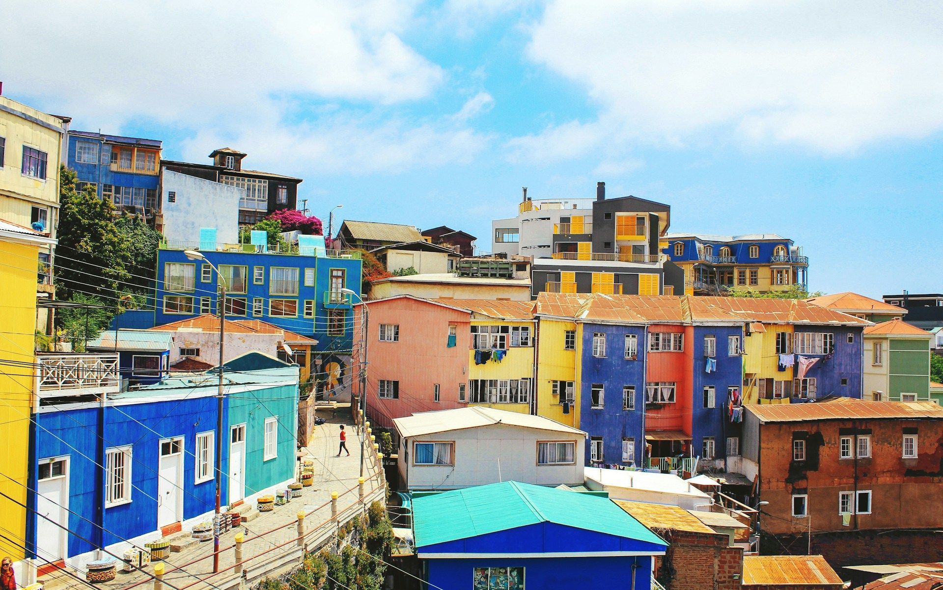 Un denso gruppo di edifici multicolori su una collina soleggiata sotto un cielo azzurro con nuvole leggere.