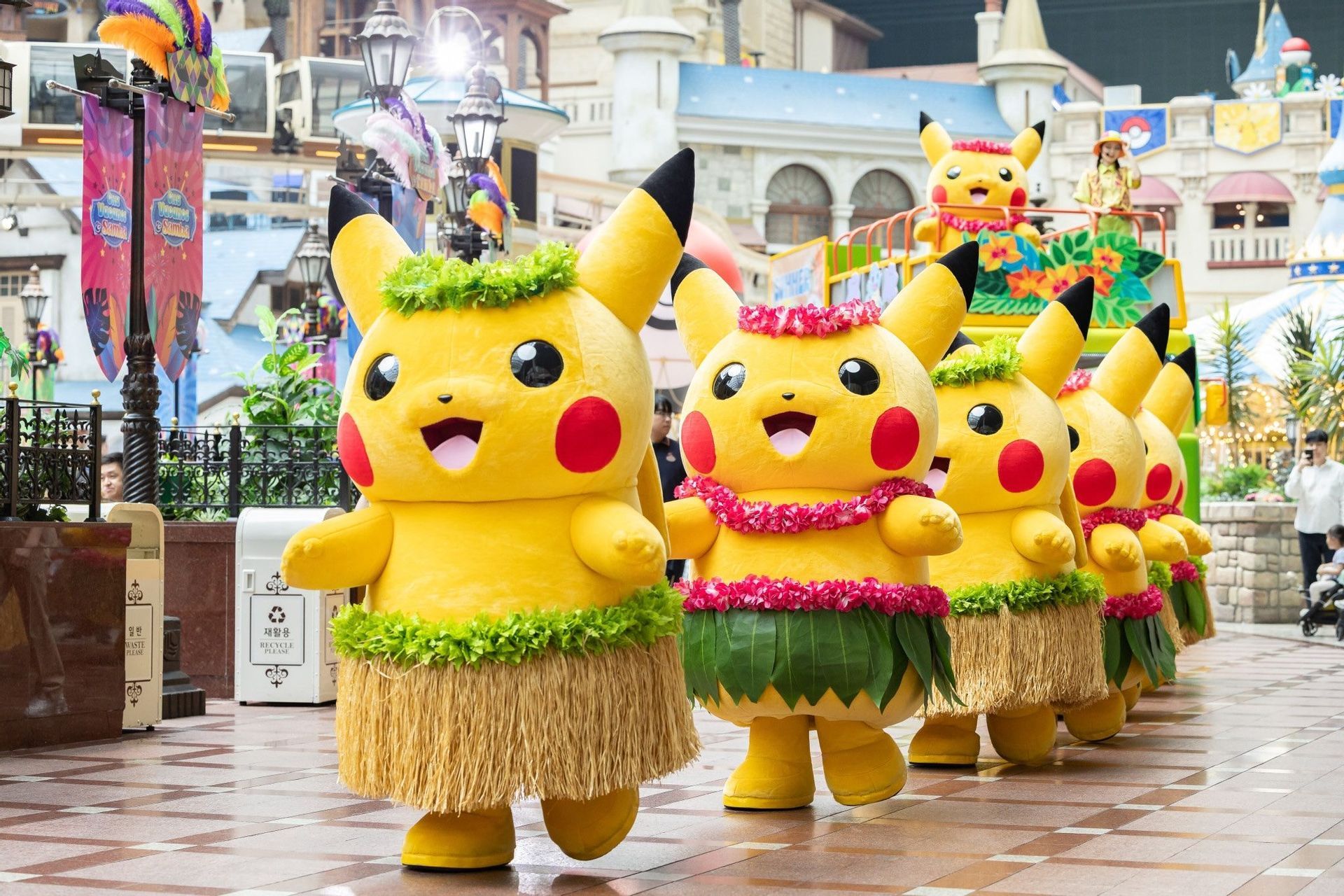 Una fila di persone in costume da Pikachu che indossano gonne di paglia e lei in stile hawaiano sfilano in parata.
