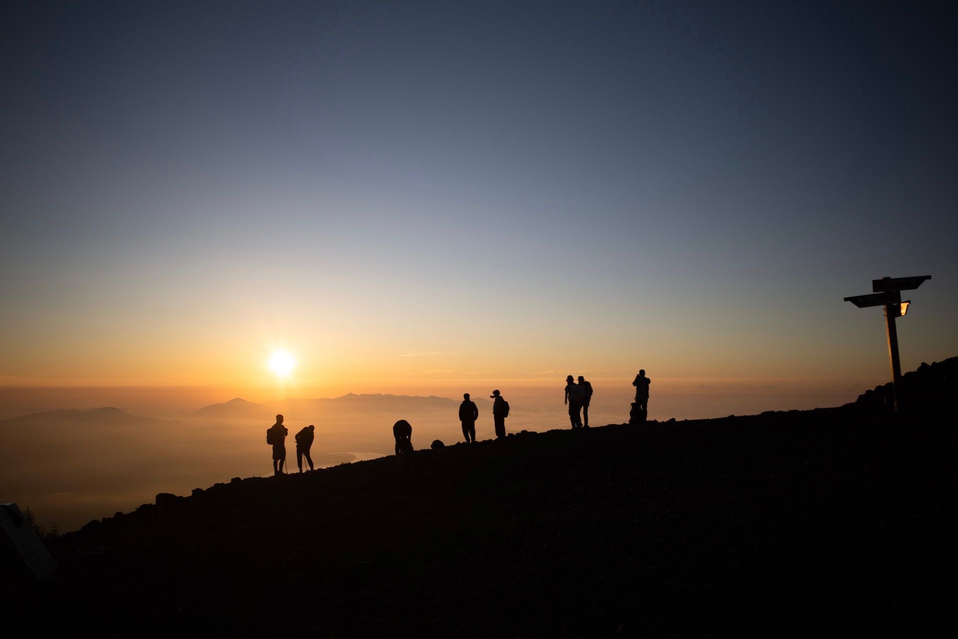 Un gruppo WeRoad in viaggio, stagliato su una cima di montagna, osserva l'alba su un mare di nuvole.