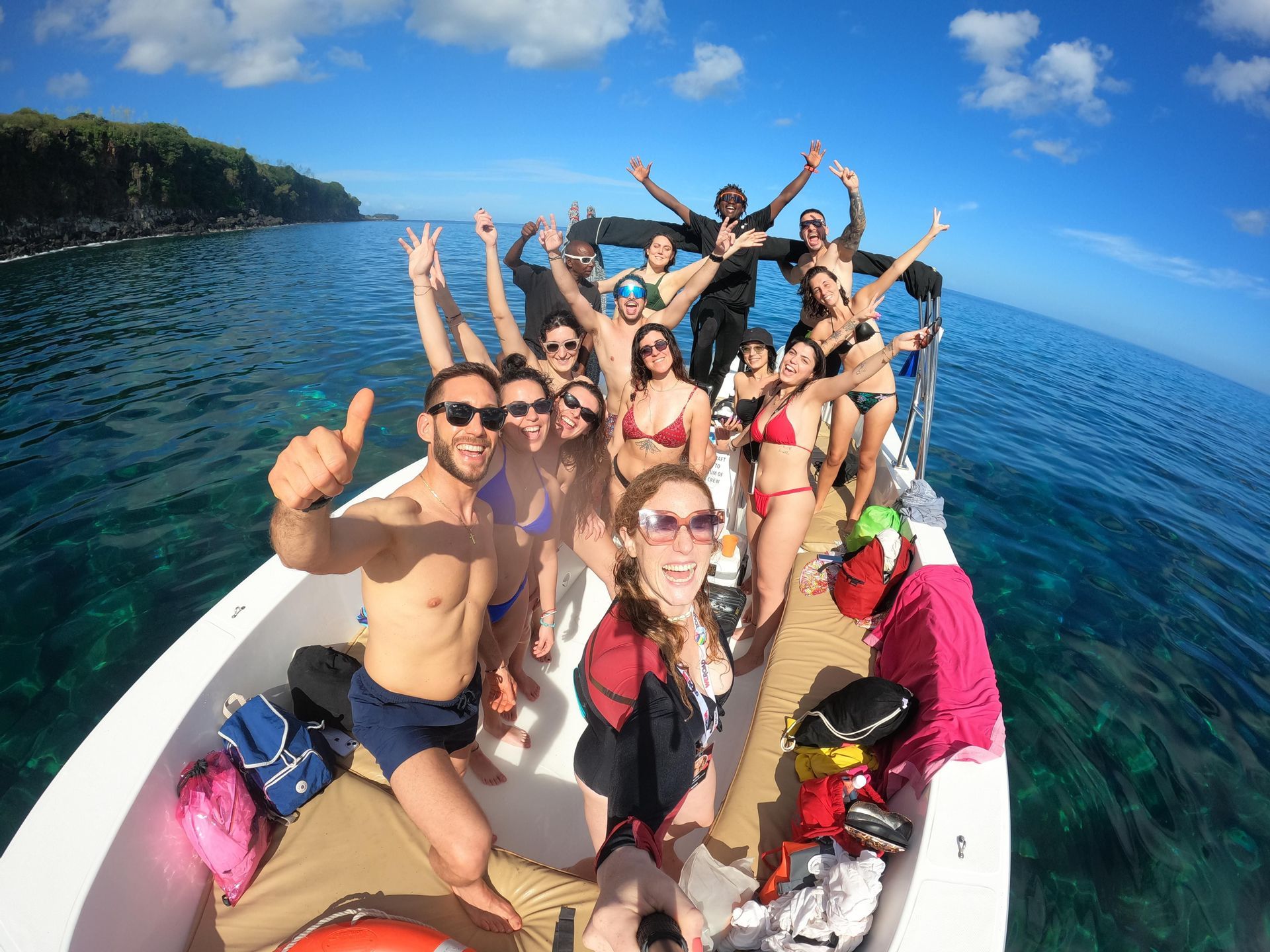 Un gruppo WeRoad sorride e posa per un selfie grandangolare su una barca in acqua limpida e turchese.