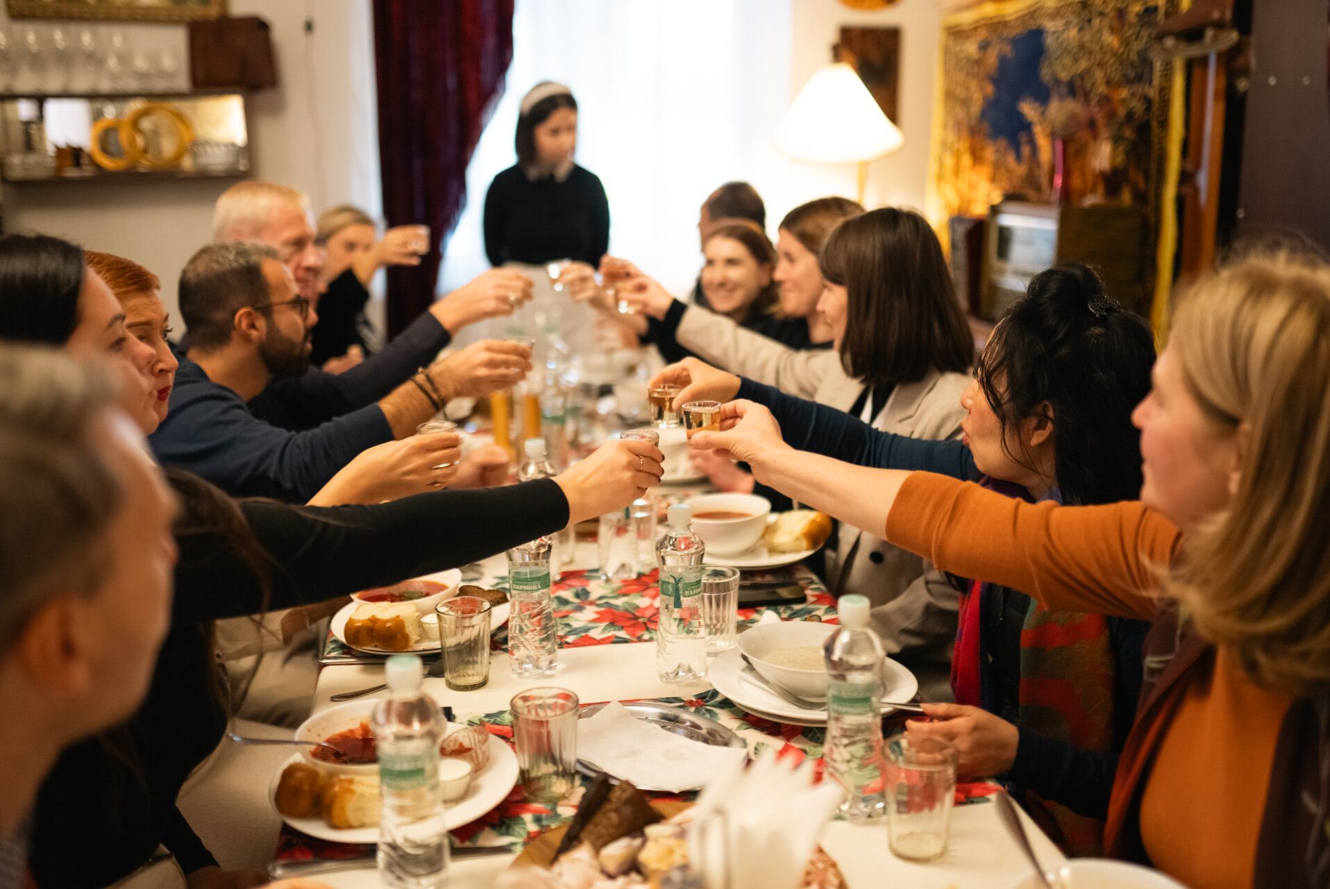 Un gruppo WeRoad a un lungo tavolo da cena, alza i calici per un brindisi.