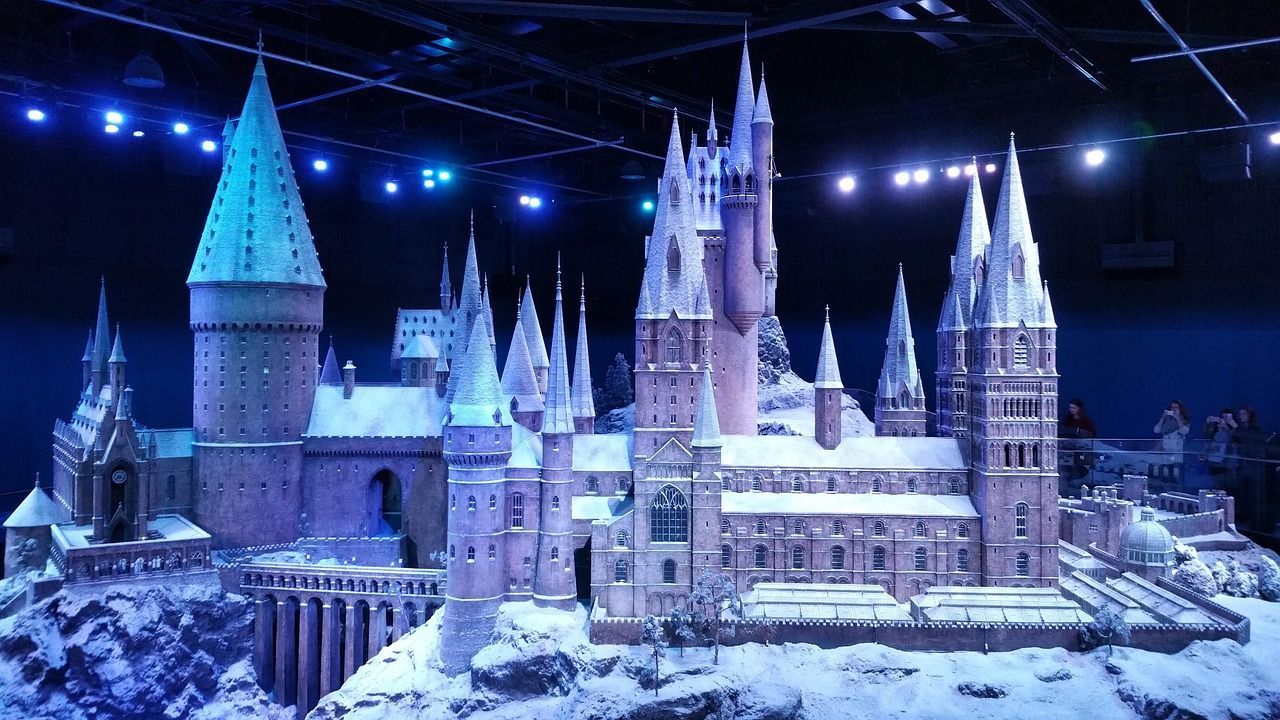 Ein detailliertes Miniaturmodell einer ausgedehnten Burg mit zahlreichen Türmen und Zinnen, schneebedeckt und von kühlen blauen Lichtern beleuchtet.