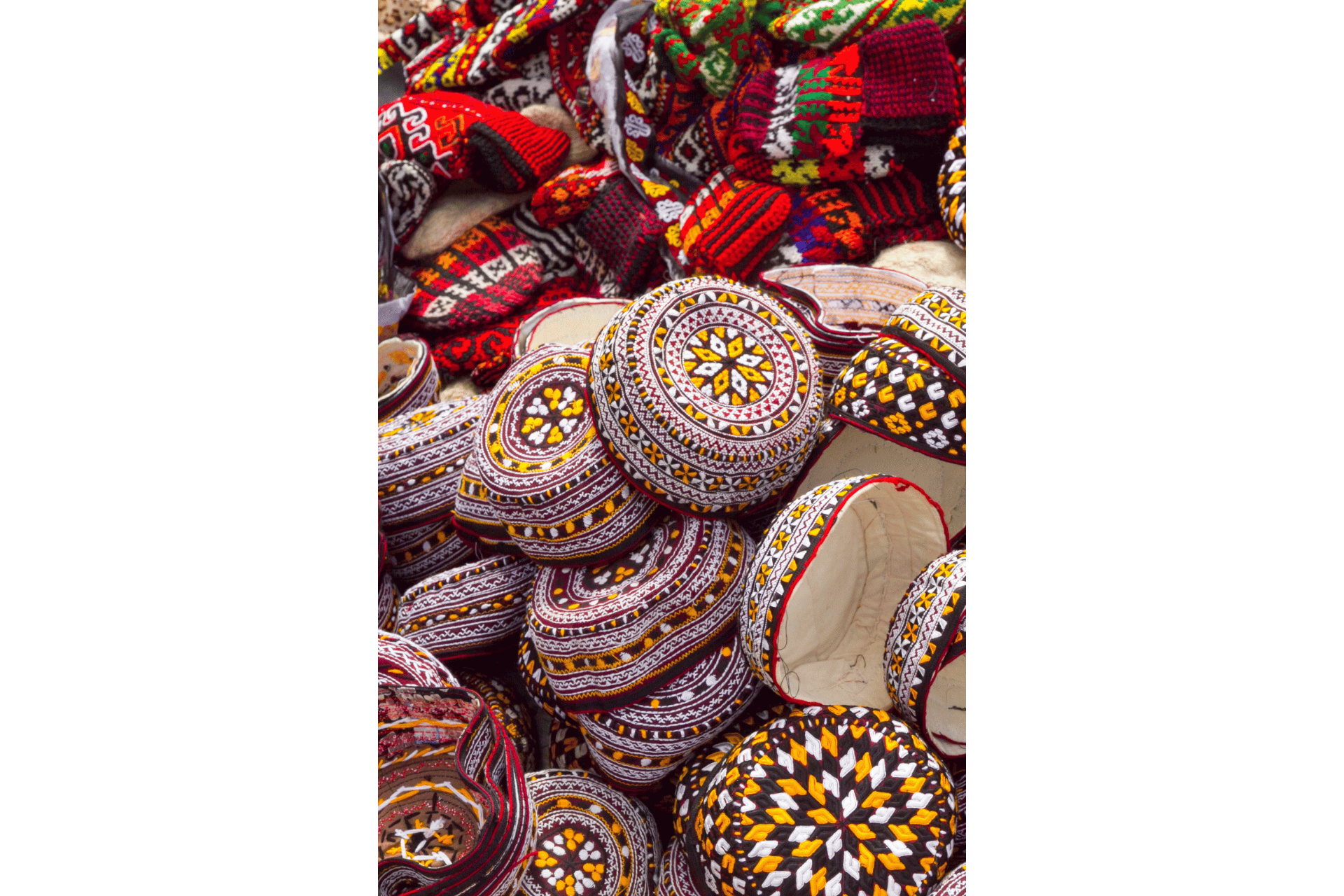 Un grande mucchio di colorati zuccotti e berretti di lana tradizionalmente ricamati con vari motivi geometrici.