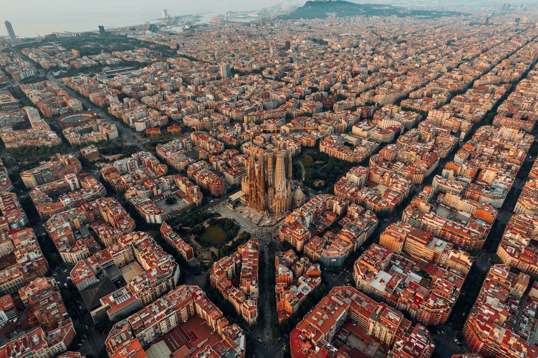 Vista aerea di una grande e ornata cattedrale nel centro di una città fitta con pianta a griglia, al tramonto.