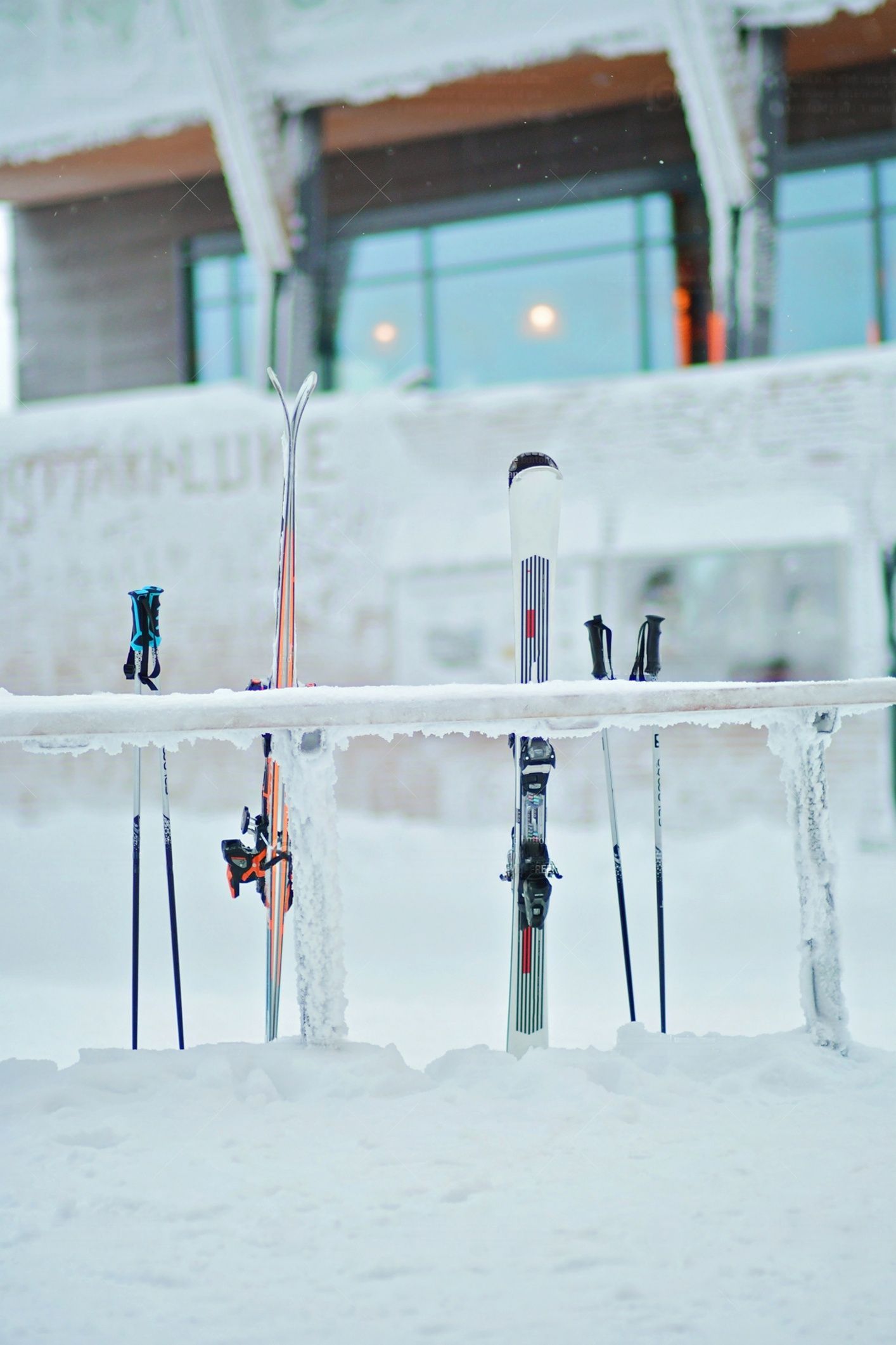 Ski und Stöcke stehen im tiefen Schnee und lehnen an einem vollständig mit Eis und Schnee bedeckten Gestell.