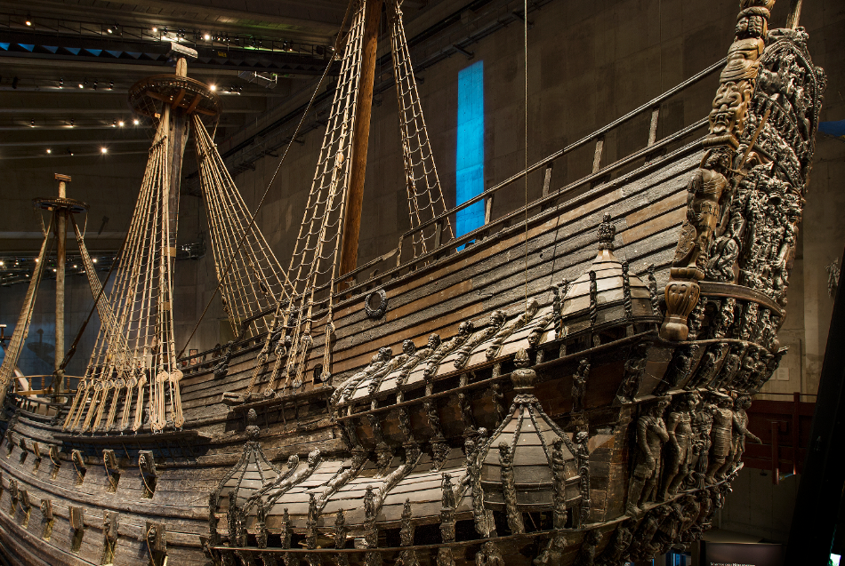 Una grande e storica nave da guerra in legno, con intarsi intricati sullo scafo e sulla prua, esposta all'interno di un museo.