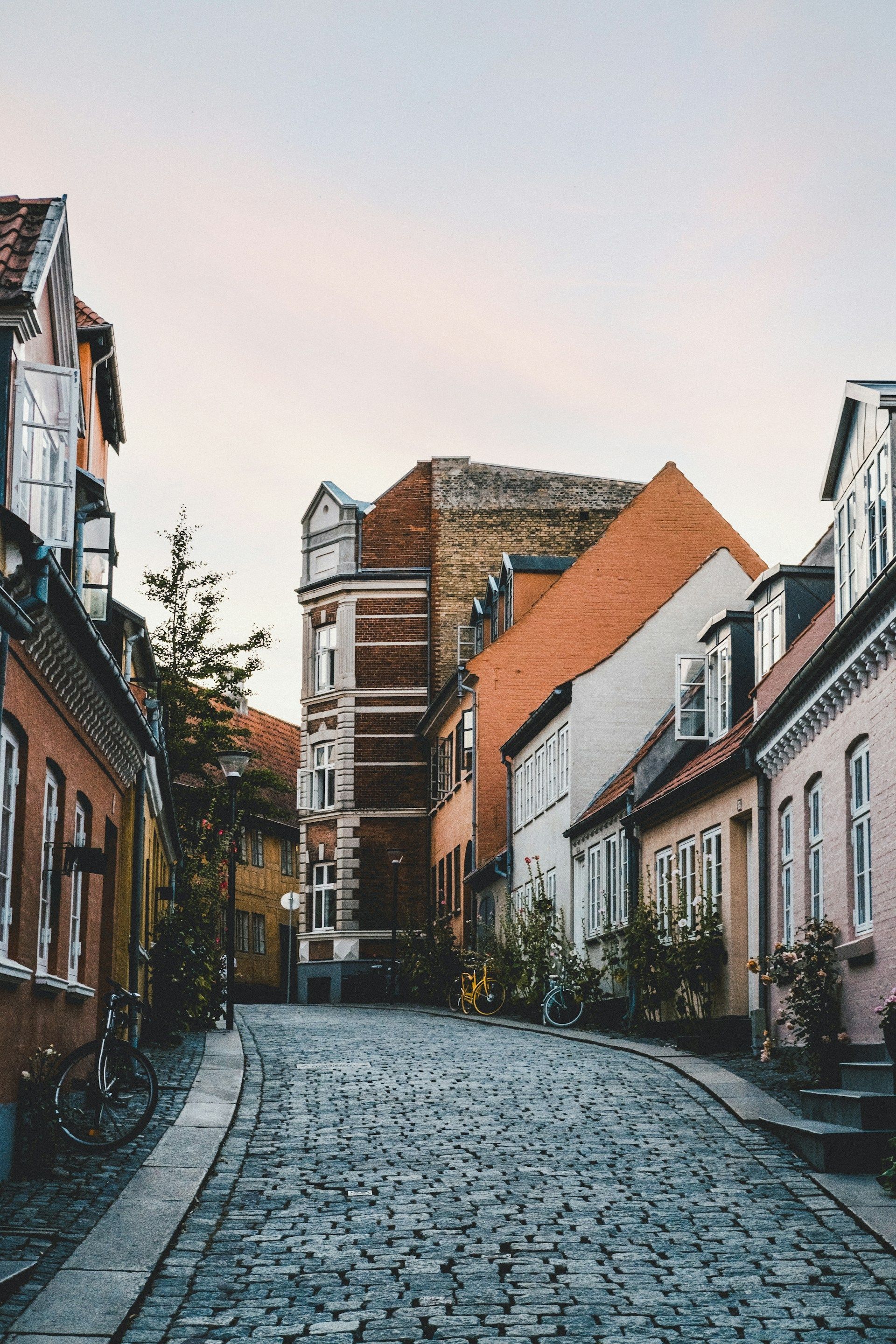 Una calle adoquinada y curva está flanqueada por coloridos edificios históricos con varias bicicletas aparcadas a su lado.