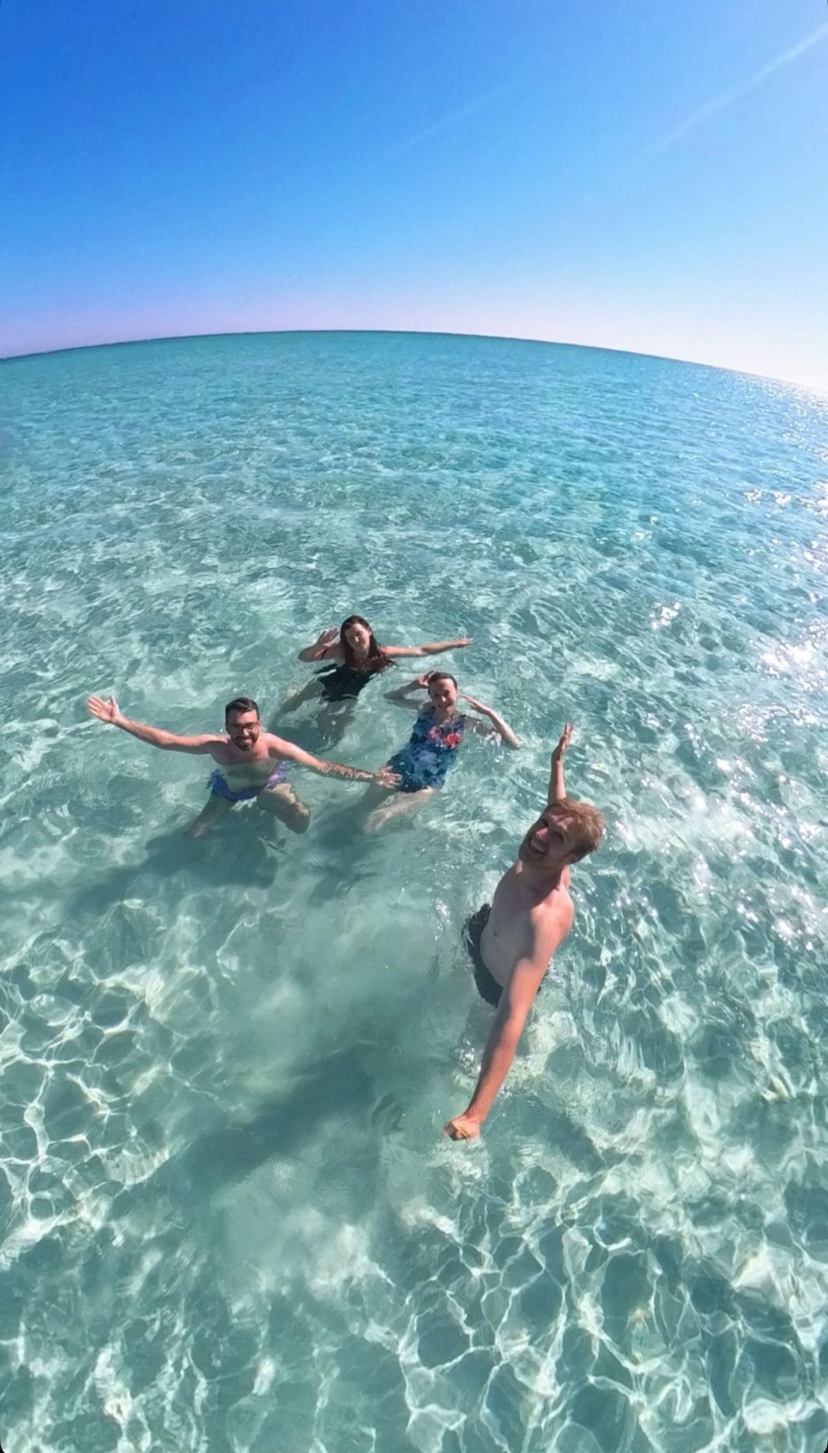 Un viaggio di gruppo WeRoad di quattro persone che si scattano un selfie mentre nuotano in acque limpide e turchesi sotto un cielo azzurro.