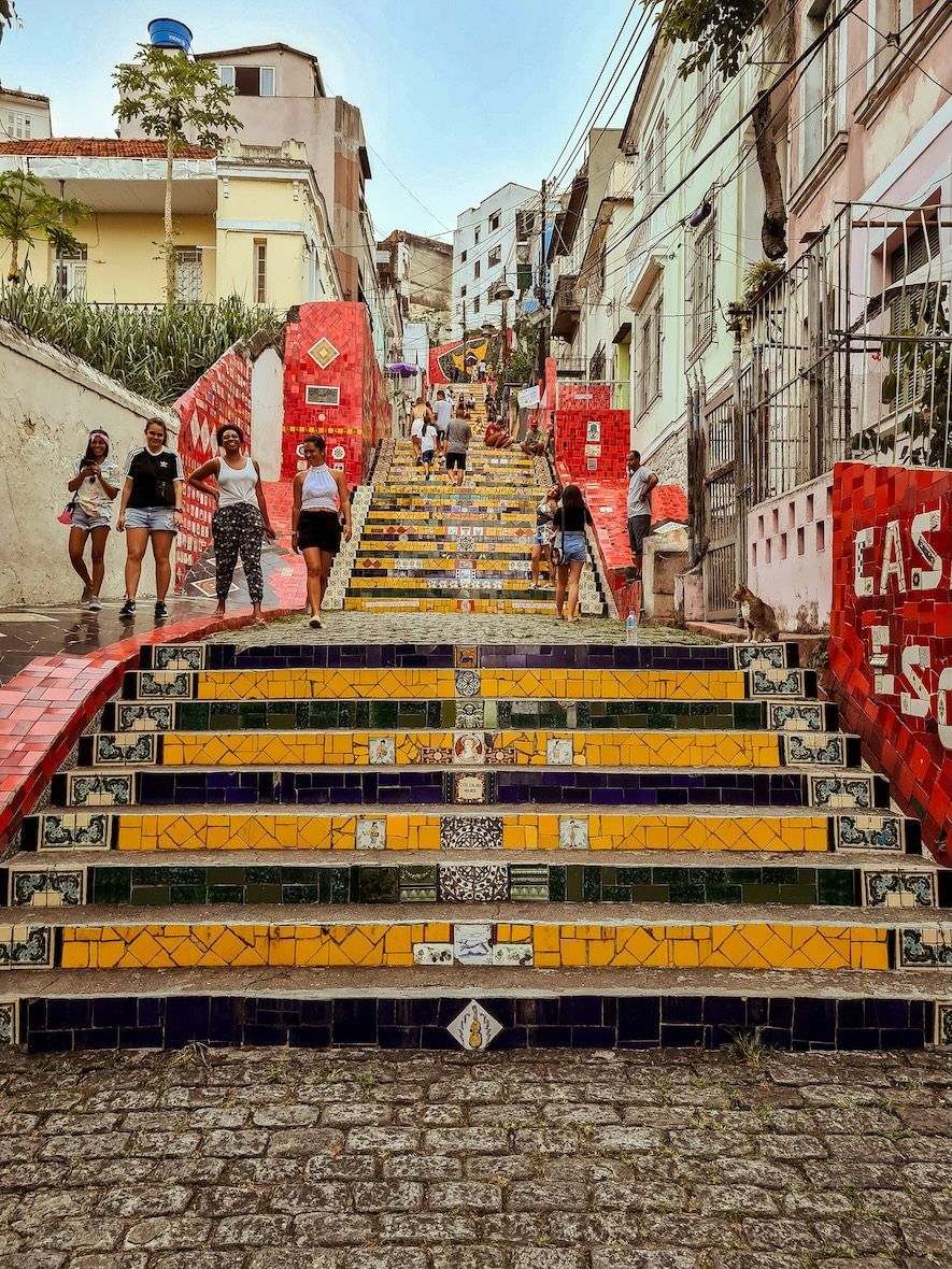 A WeRoad group trip poses on a long staircase decorated with colorful yellow, blue, and red mosaic tiles.