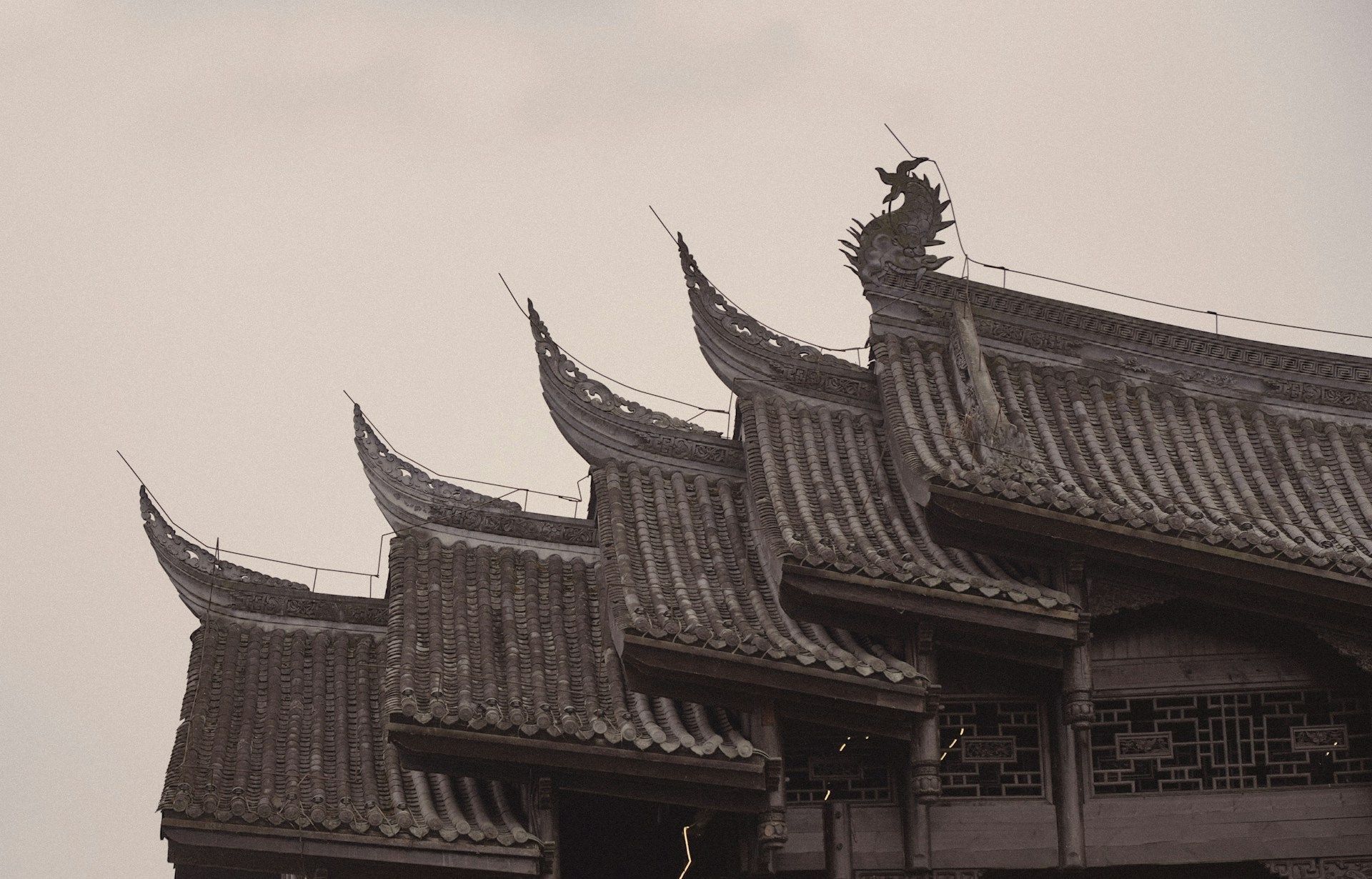 Una fotografia in bianco e nero che mostra i tetti a tegole stratificati e decorati di un tradizionale edificio dell'Asia orientale.