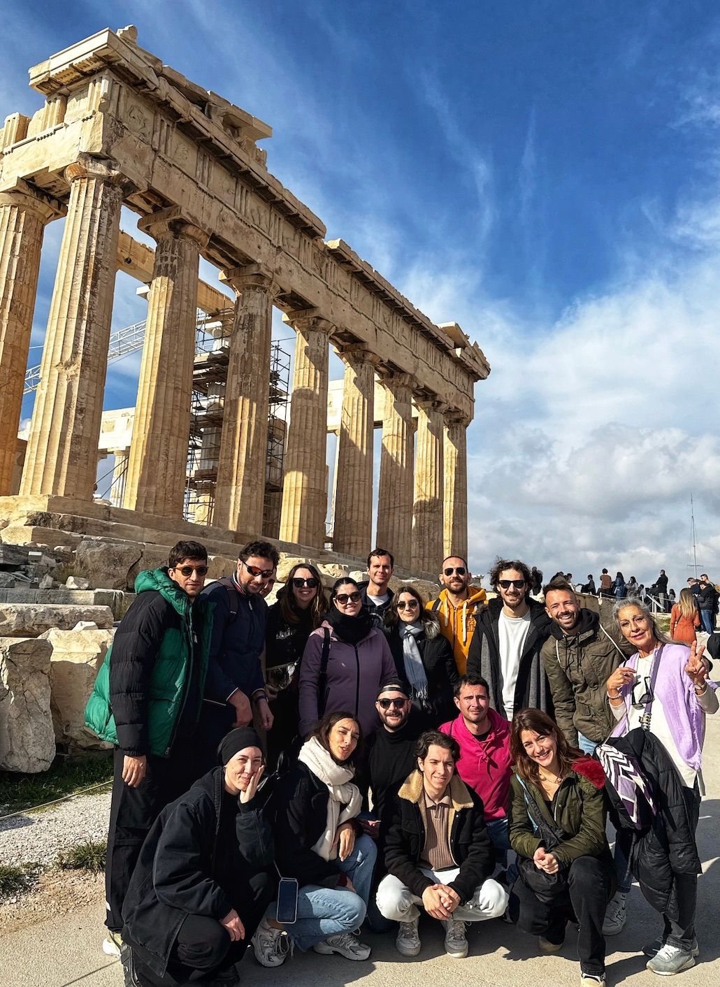 Un voyage de groupe WeRoad posant pour une photo devant un grand temple classique avec des colonnes en pierre sous un ciel bleu.