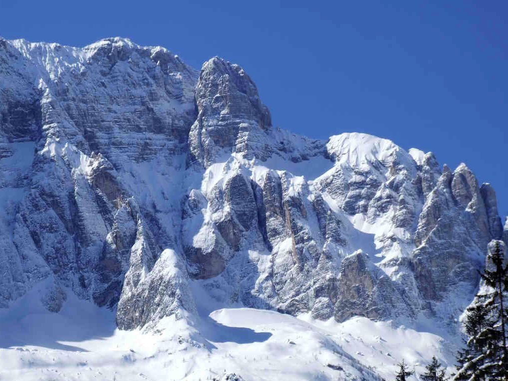 Le aspre cime rocciose delle montagne sono ricoperte da uno spesso strato di neve sotto un limpido cielo azzurro.