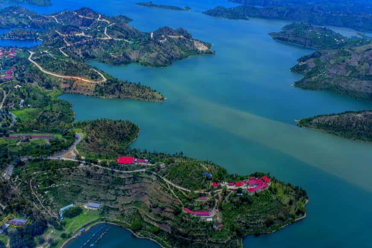 Vue aérienne d'un vaste lac turquoise entouré de péninsules et d'îles verdoyantes et vallonnées avec de petits villages.